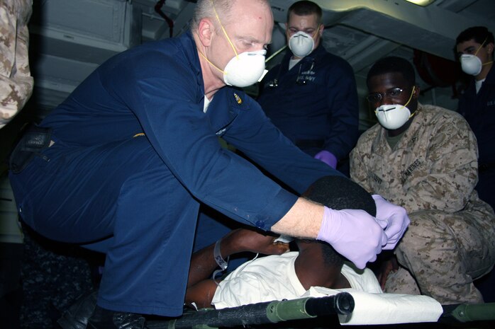 Senior Chief Scott Rudlec, hospital corpsman, USS NASSAU, treats a Haiti national following an emergency medivac where two men and two children, including an infant, were flown from  USNS Comfort to USS Nassau for medical treatment.  Marines and Sailors wth the 24th Marine Expeditionary Unit and Nassau Amphibious Readiness Group responded immediately when called upon and had the injured moved in 15 minutes, using the versatility of a sea-based expiditionary force to its fullest potential.