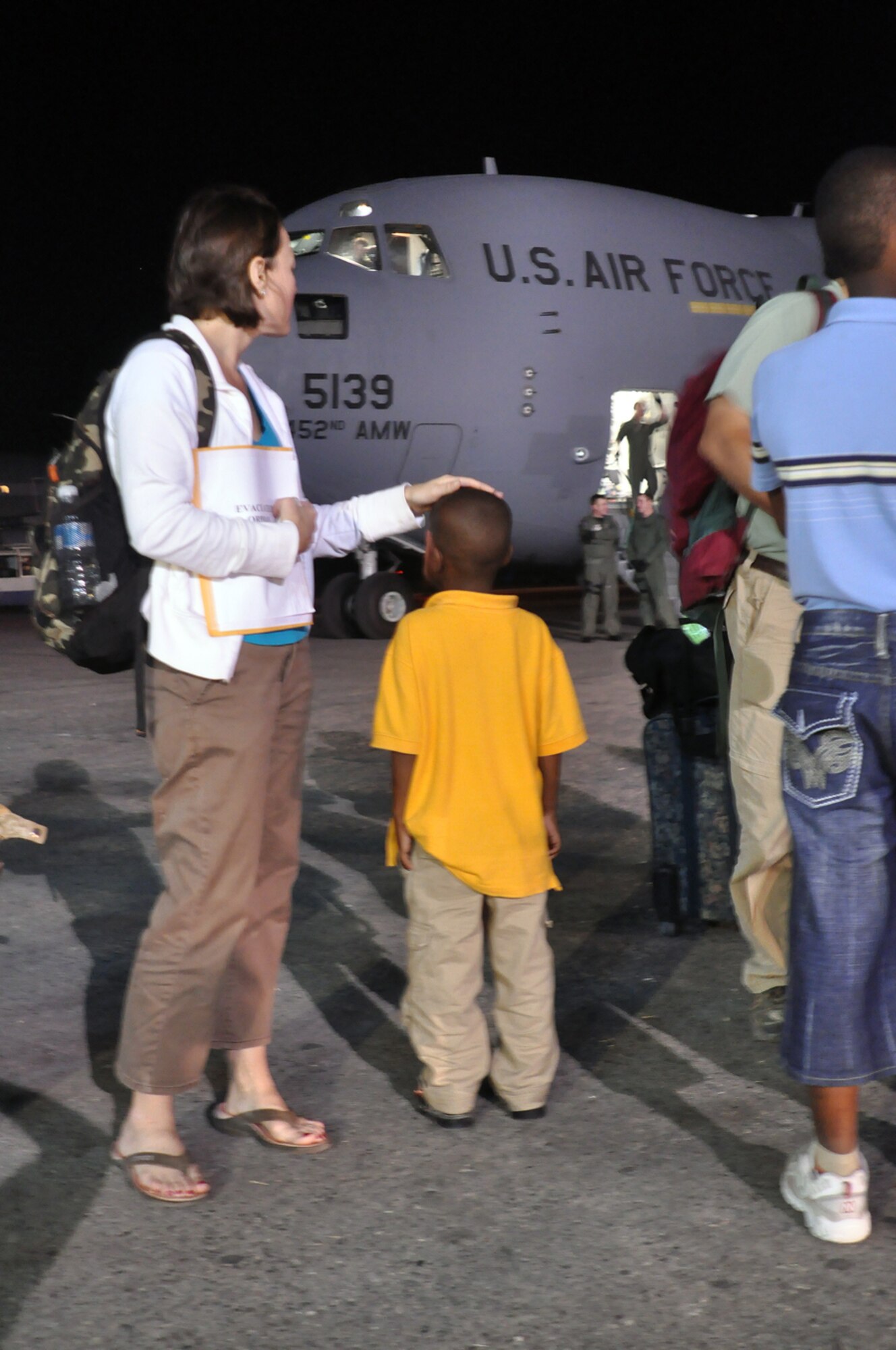 Ms. Erin Pemungia and her newly adopted son, Noah, age 7, wait to board an Air Force Reserve C-17 aircraft from the 452nd Air Mobility Wing, March Air Force Base, Calif. The aircraft traveled to Port-au-Prince Jan. 22 to deliver 15 personnel and equipment from the 419th Fighter Wing’s 67th Aerial Port Squadron. The 67th APS members will be deployed to Port-au-Prince for at least 45 days and will assist with airfield operations. The aerial porters, all volunteers, will help pave the way for increased U.S. humanitarian aid in the aftermath of last week’s devastating earthquake. Prior to returning to the United States, the C-17 took on 54 passengers, including Ms. Pemungia and Noah. Most were Haitian orphans traveling to the U.S. to be united with their adoptive parents. (U.S. Air Force Photo/Kari Tilton)