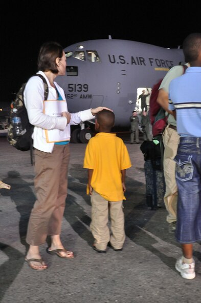 Ms. Erin Pemungia and her newly adopted son, Noah, age 7, wait to board an Air Force Reserve C-17 aircraft from the 452nd Air Mobility Wing, March Air Reserve Base, Calif. The aircraft traveled to Port-au-Prince Jan. 22 to deliver 15 personnel and equipment from the 419th Fighter Wing’s 67th Aerial Port Squadron. The 67th APS members will be deployed to Port-au-Prince for at least 45 days and will assist with airfield operations. The aerial porters, all volunteers, will help pave the way for increased U.S. humanitarian aid in the aftermath of last week’s devastating earthquake. Prior to returning to the United States, the C-17 took on 54 passengers, including Ms. Pemungia and Noah. Most were Haitian orphans traveling to the U.S. to be united with their adoptive parents. (U.S. Air Force Photo/Kari Tilton) 