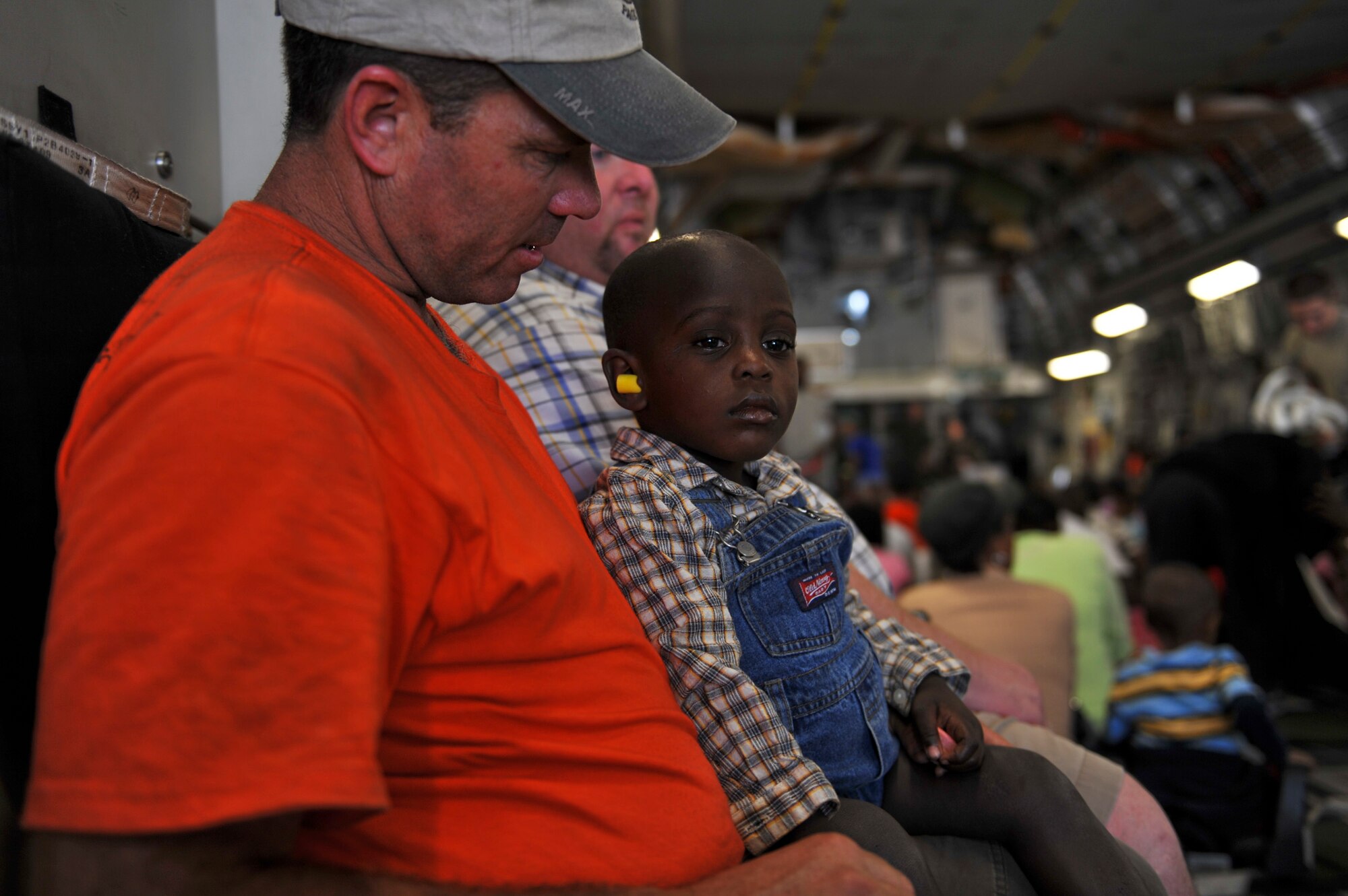 A Haitian boy watches as nearly 200 Haitians board a C-17 Globemaster III at Toussaint L'Ouverture International Airport in Port-au-Prince, Haiti, Jan. 23, 2010.  Aircraft from all over the world are flying into the airport  to drop off humanitarian aid and transport people out of the country in the aftermath of the devastating earthquake Jan. 12.  (U.S. Air Force photo/Staff Sgt. Desiree N. Palacios)
