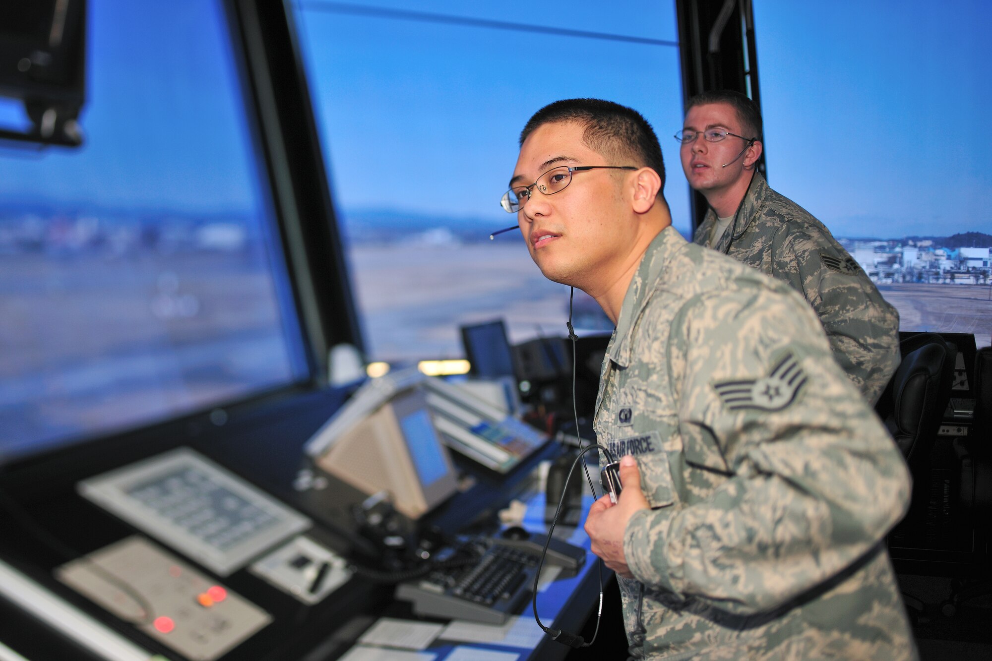 YOKOTA AIR BASE, Japan -- Staff Sgt. Tyler Stocks (front) and Senior Airman Shawn Hamm (back), 374th Operations Support Squadron air traffic controllers, confirm an aircraft is landing safely visually and by radio communication at the newest control tower here, Jan. 22. (U.S. Air Force photo/Osakabe Yasuo)
