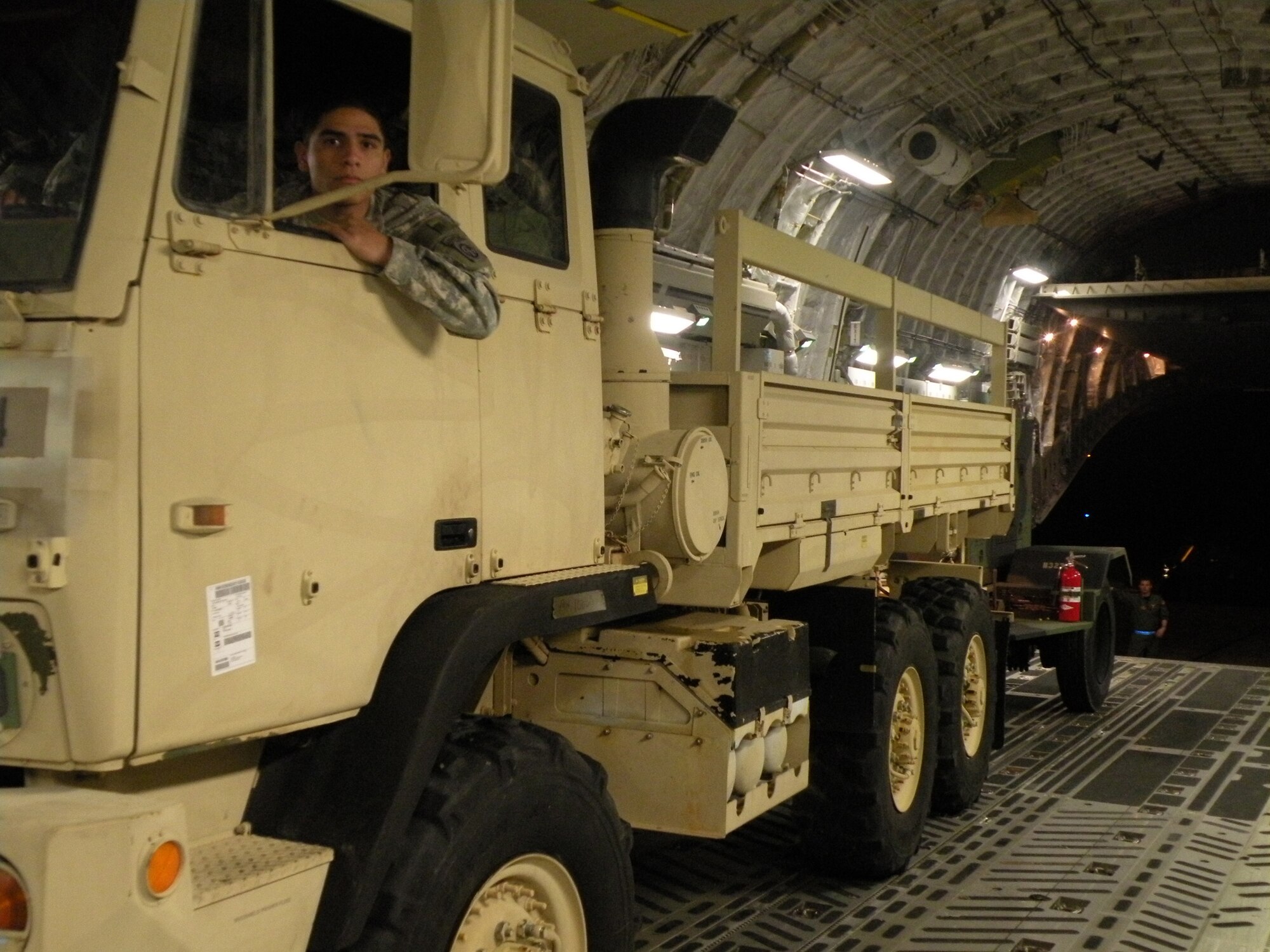A soldier from Fort Bragg, N.C. looks out his rear view mirror as Staff Sgt. Gus Morse, a Reserve loadmaster from the 317th Airlift Squadron, Charleston Air Force Base, S.C., guides him and his vehicle out the back of a C-17 Globemaster III after landing in Haiti in support of Operation Unified Response during the early morning hours of Jan. 22, 2010. (U.S. Air Force Photo/Master Sgt. Steve Staedler)                              