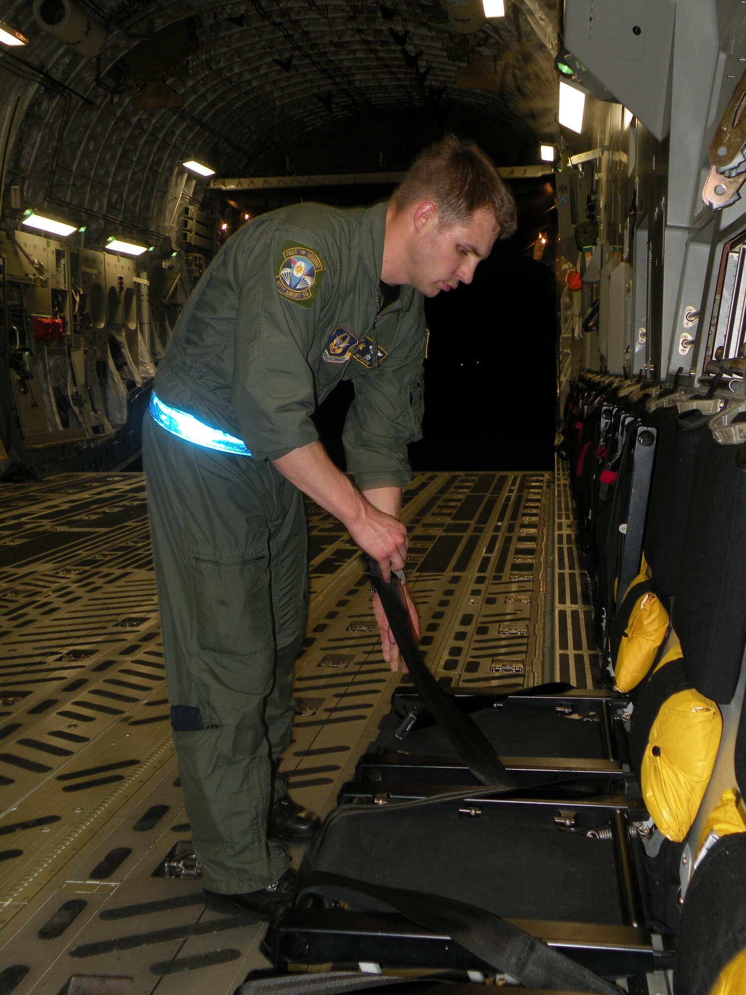 Staff Sgt. Gus Morse, a Reserve loadmaster from the 317th Airlift Squadron, Charleston Air Force Base, S.C., prepares seats to transport Haitian passengers to Orlando on a C-17 Globemaster III in support of Operation Unified Response during the early morning hours of Jan. 22, 2010. (U.S. Air Force Photo/Master Sgt. Steve Staedler)