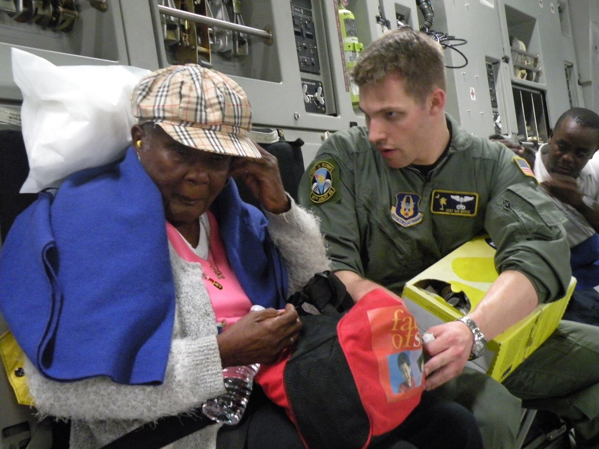Staff Sgt. Gus Morse, a Reserve C-17 loadmaster from the 317th Airlift Squadron, Charleston Air Force Base, S.C., helps a Haitian woman insert her ear plugs prior to departure to Orlando during the early morning hours of Jan. 22, 2010. (U.S. Air Force Photo/Master Sgt. Steve Staedler)                                         
