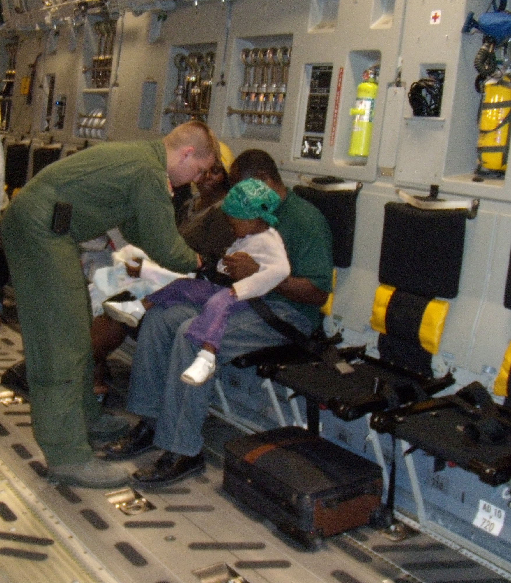 Airman First Class Landon Greenwood, 3rd Airlift Squadron loadmaster, helps safely buckle in a young girl being evacuated out of Port-au-Prince, Haiti on a Dover C-17 Globemaster III Jan. 19. The C-17 crew dropped off 90,000 pounds of cargo in Haiti and picked up 36 evacuees in support of Operation Unified Response. (U.S. photo/2d Lt Abigail Wise)