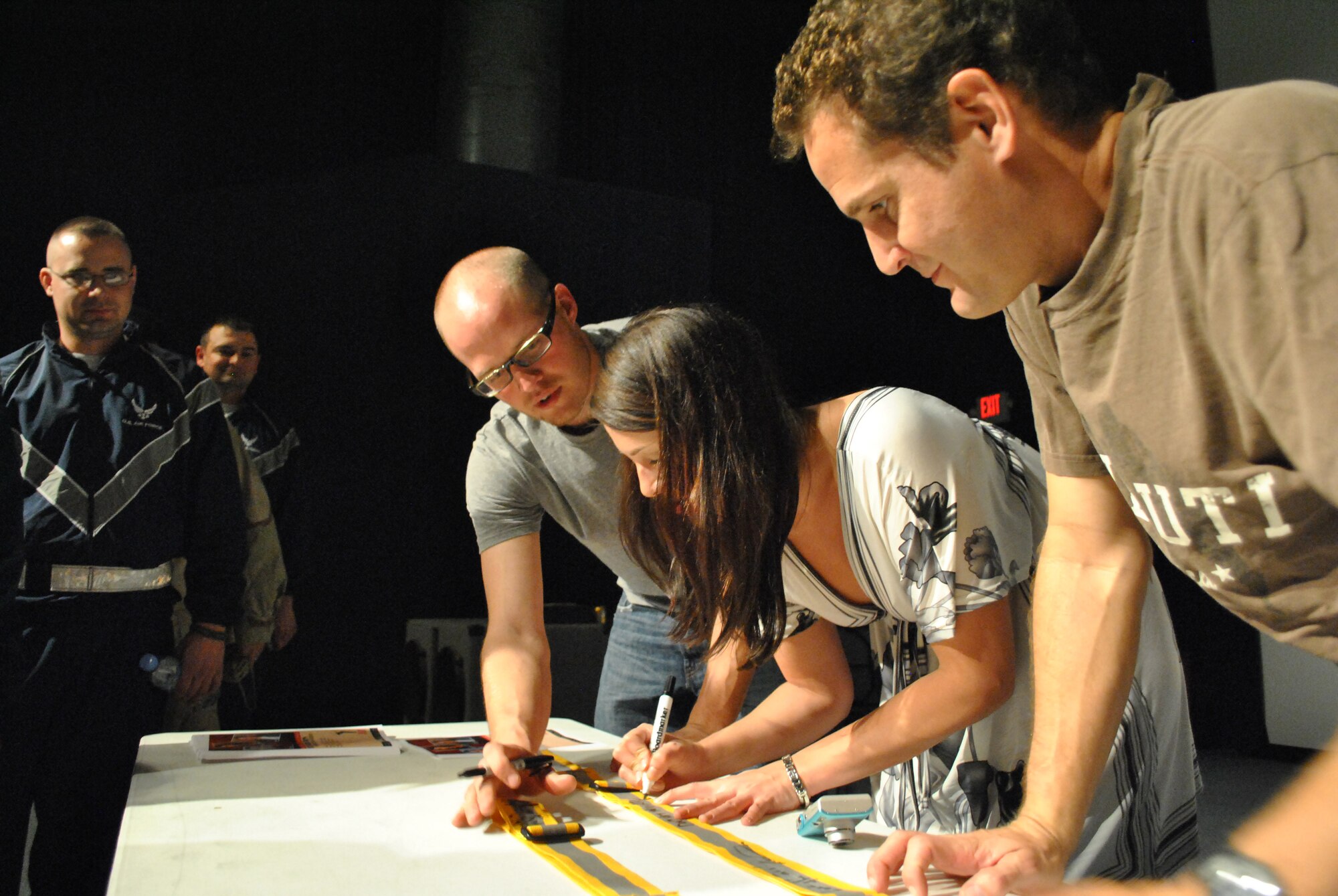 Matt Baetz, Lauren Ashley Bishop and Johnny Cardinale, Comedy Corps performers, autograph reflective safety belts following a performance at the Coalition Compound Theatre at a non-disclosed Southwest Asia location, Jan. 23, 2010. The comedy troupe is scheduled to appear at various locations throughout the AOR. (U.S. Air Force photo by Senior Master Sgt. David Byron) [RELEASED]