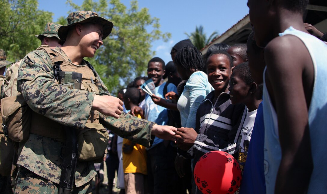 Lance Cpl. Zhidong Mao, a rifleman with Lima Company, Battalion Landing Team, 3rd Battalion, 2nd Marine Regiment, 22nd Marine Expeditionary Unit, shakes hands with a Haitian child at a helicopter landing zone in Leogane, Haiti, Jan. 24, 2010. The Marines flew into the area earlier in the day establishing a new humanitarian aid receiving area for Haitian earthquake victims at a missionary compound.