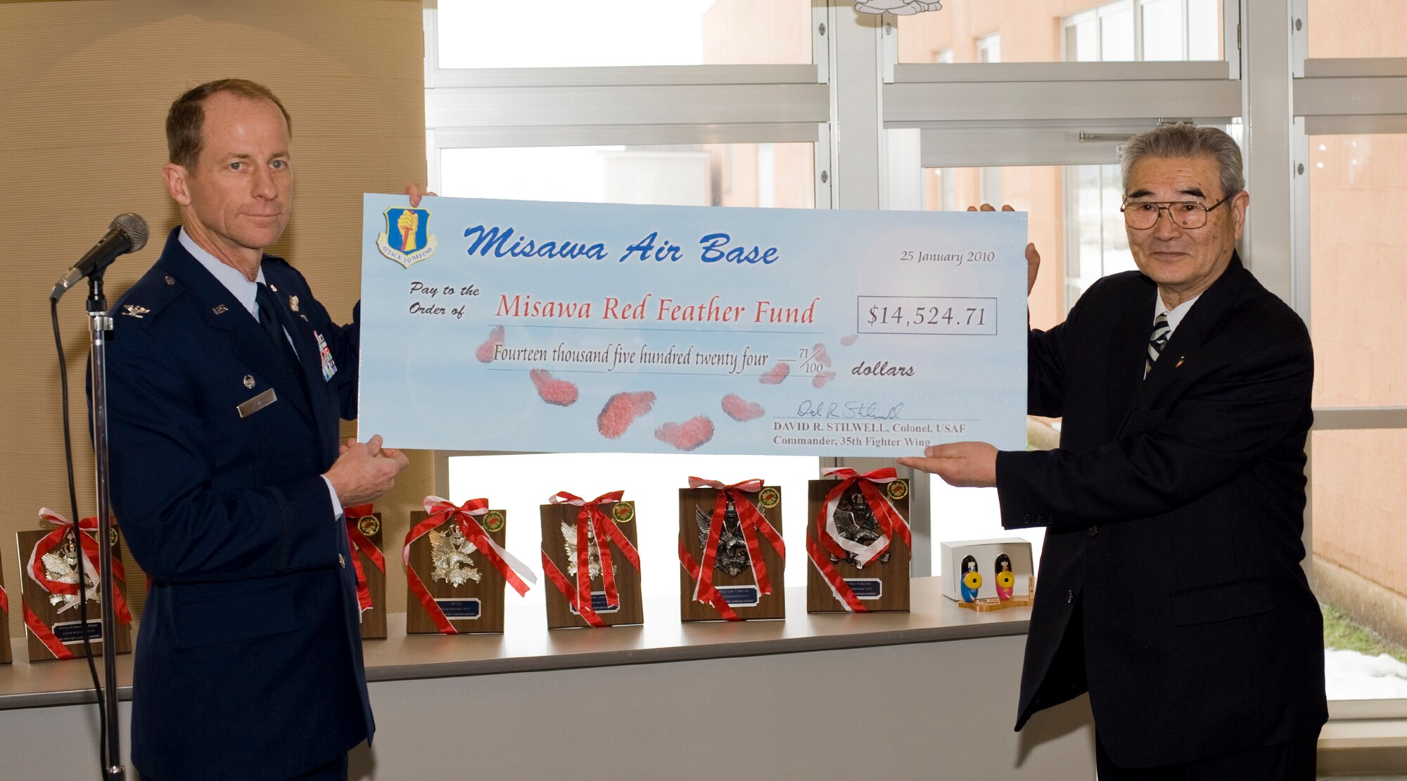MISAWA CITY, Japan -- Col. David Stilwell, 35th Fighter Wing commander, presents the Misawa Air Base Red Feather Campaign contribution to Mr. Ishi Numata, Misawa Red Feather Community Chest Committee president, Jan. 25 at the Misawa International Center. Misawa Air Base donated more than $14,000 during the 2009 campaign, compared to a donation of $8,000 in the previous year. The money will help provide assistance to under-privileged children, the elderly and handicapped citizens of Misawa City. (U.S. Air Force photo/Senior Airman Jamal D. Sutter)