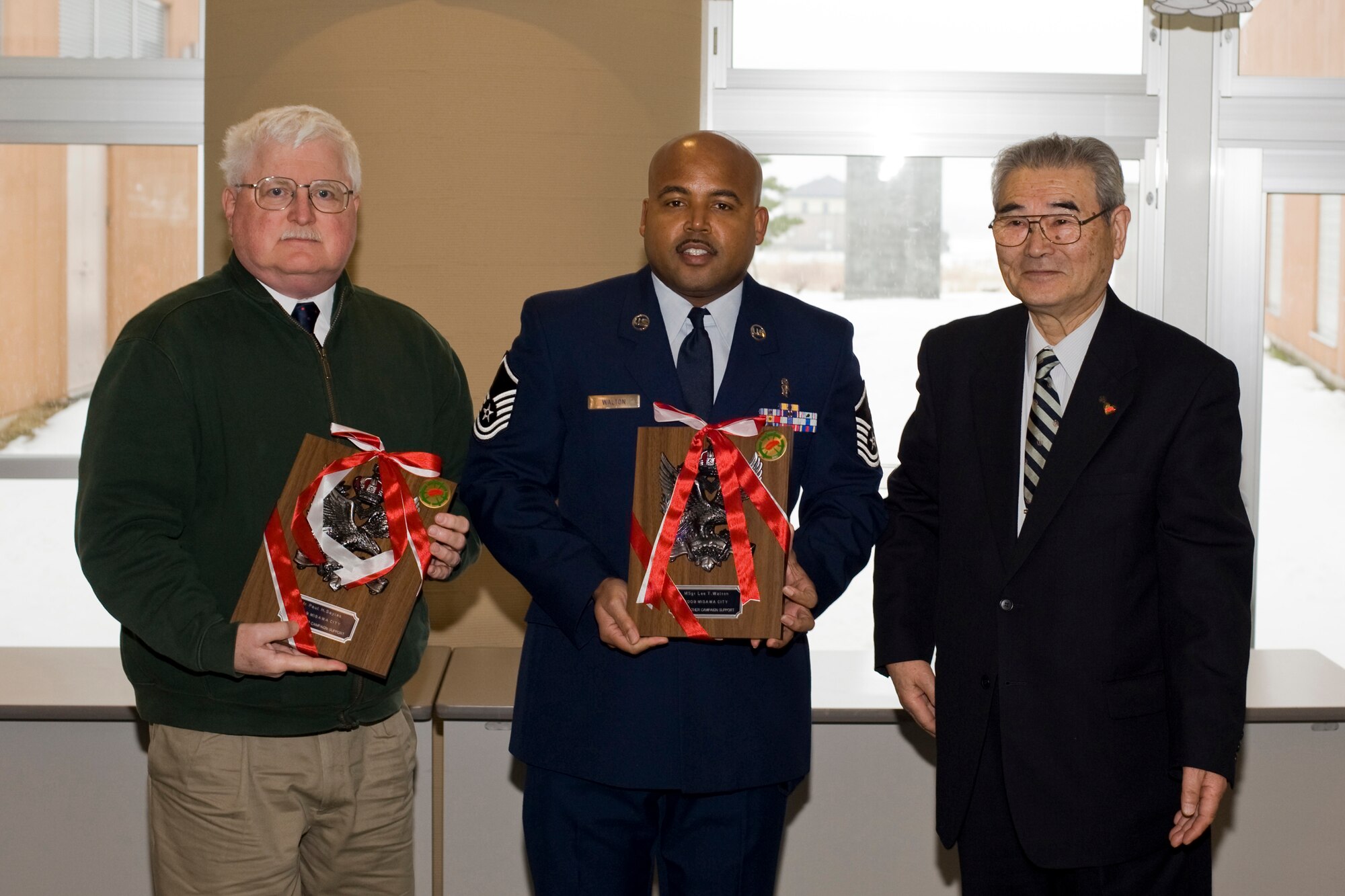 MISAWA CITY, Japan -- Mr. Paul Sayles, 35th Aerospace Medicine Squadron patient safety representative, and Master Sgt. Lee Walton, 35th Dental Squadron clinic flight chief, receive plaques from Mr. Ishi Numata, Misawa Red Feather Community Chest Committee president, during a check presentation ceremony Jan. 25 at the Misawa International Center. Mr. Sayles and Sergeant Walton served as project officers for the campaign, and Mr. Numata thanked them for their contributions and support throughout the effort. (U.S. Air Force photo/Senior Airman Jamal D. Sutter)