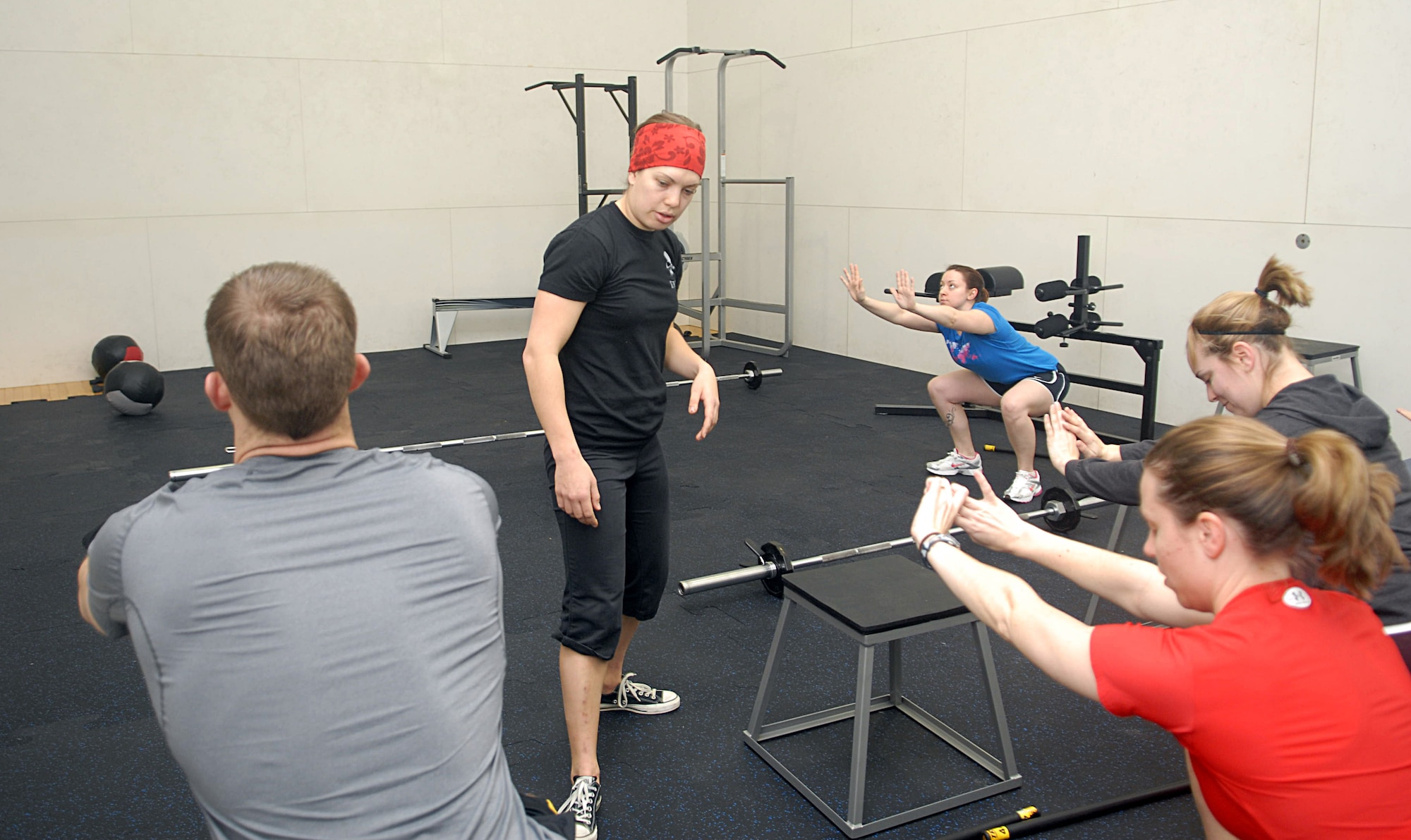 KUNSAN AIR BASE, Republic of Korea -- 1st Lt Kari Kundert, 8th Operations Group, instructs fellow Wolf Pack members on proper squat form during a CrossFit work out at the fitness Center Jan. 23. The first fitness assessment and fundamental class begins Jan. 30 from 10 a.m. to 1 p.m. at the fitness center. Sign up for the class at wolfpackcrossfit.com only 25 per class. (U.S. Air Force photo/Senior Airman Roy Lynch)