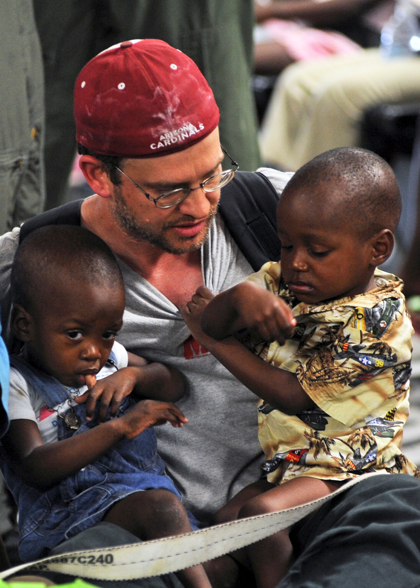 PORT-AU-PRINCE, Haiti --A Haiti relief volunteer holds two infants aboard a C-17 Globemaster III flown by pilots from the 517th and 249th airlift squadrons, assigned to Elmendorf Air Force Base, Jan. 23. The crew picked up 80 orphans along with volunteers and families and brought them to Orlando, Fla., where their adoptive families met them. (U.S. Air Force photo/Senior Airman Laura Turner)