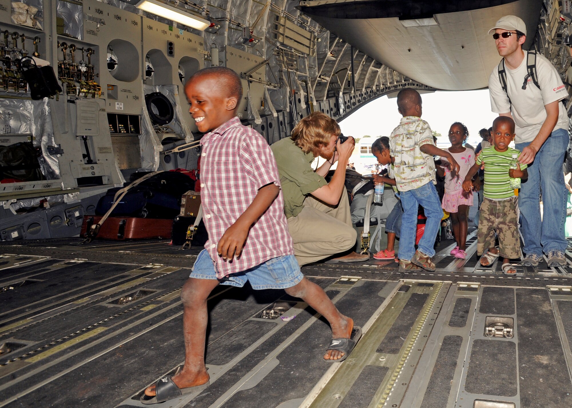 PORT-AU-PRINCE, Haiti -- A young Haitian boy smiles as he runs in the cargo area of a C-17 Globemaster III flown by a crew from the 517th and 249th Airlift Squadrons,from Elmendorf Air Force Base, Jan. 23. The crew picked up 80 orphans along with volunteers and families to be brought to Orlando, Fla., where the orphans  met their adoptive families. (U.S. Air Force photo/Senior Airman Laura Turner)