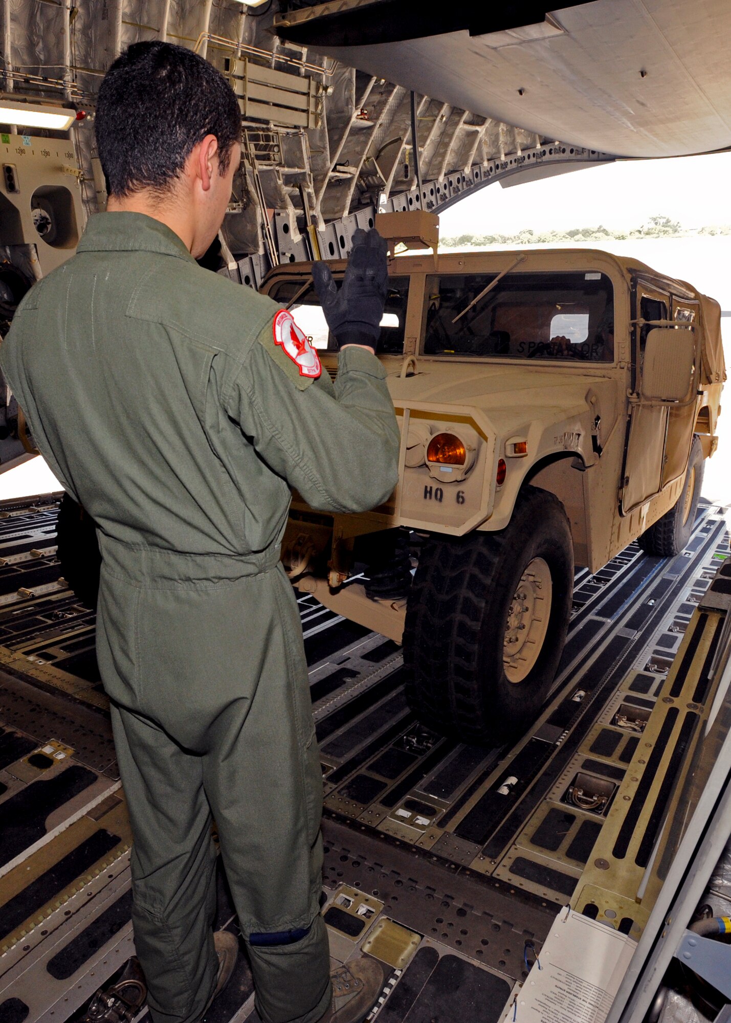 PORT-AU-PRINCE, Haiti -- Senior Airman Robert Villa, 517th Airlift Squadron, directs communication to a Humvee driver while backing off the ramp of a C-17 Globemaster III Jan. 23. The C-17, operated by a crew from the 517th and 249th Airlift Squadrons, from Elmendorf Air Force Base, delivered pallets of water and two Humvees with trailers to aid the Haiti relief effort. (U.S. Air Force photo/Senior Airman Laura Turner)
