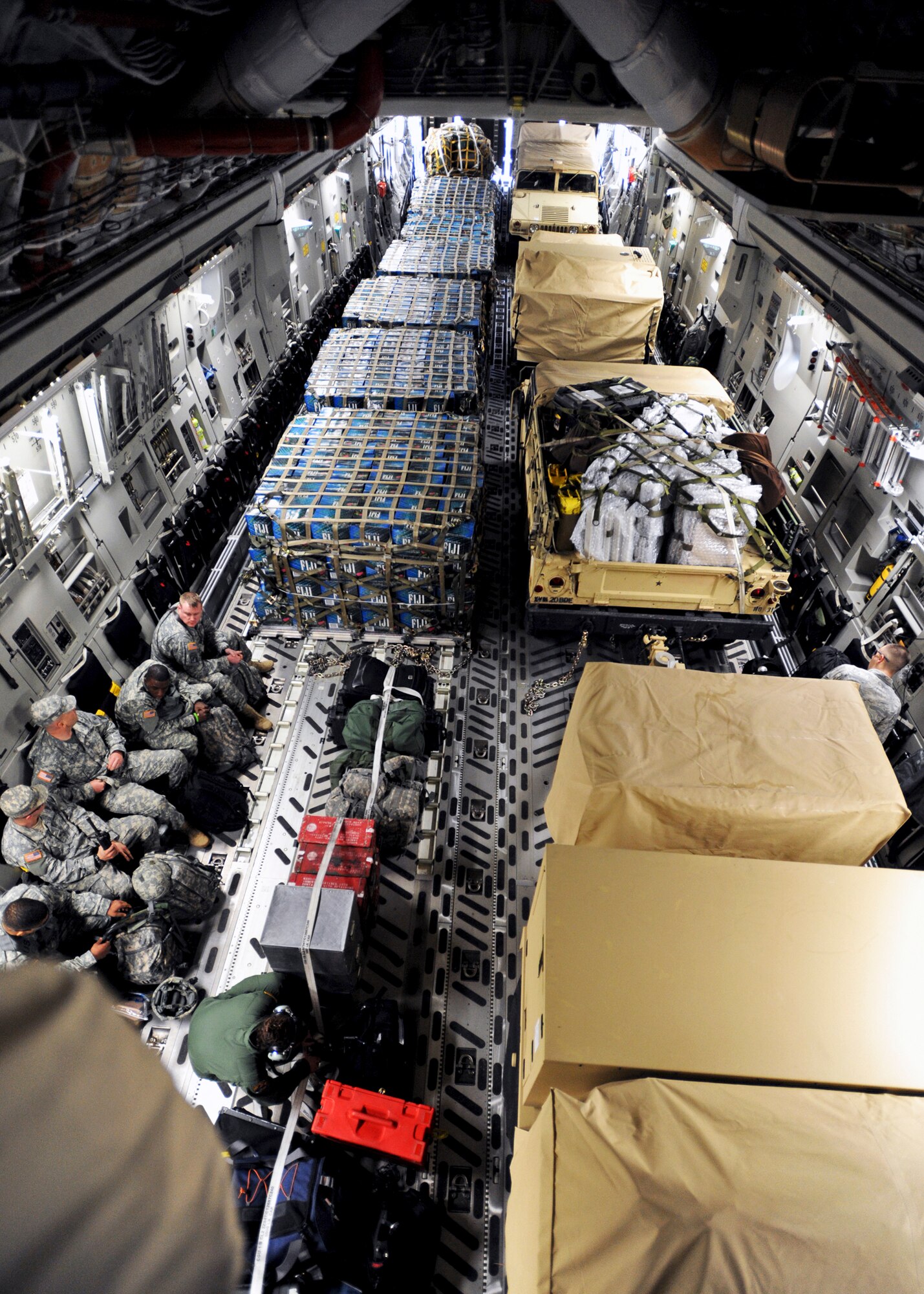 PORT-AU-PRINCE, Haiti -- A C-17 Globemaster III, operated by a crew from the 517th and 249th Airlift Squadrons, from Elmendorf Air Force Base, transports six pallets of water and two Humvees with trailers to aid the Haiti relief effort Jan. 23. The crew flies in and out of Haiti every few days, returning to Charleston Air Force Base, S.C., each time and picking up cargo in Pope Air Force Base, N.C., to be flown to Haiti. (U.S. Air Force photo/Senior Airman Laura Turner)
