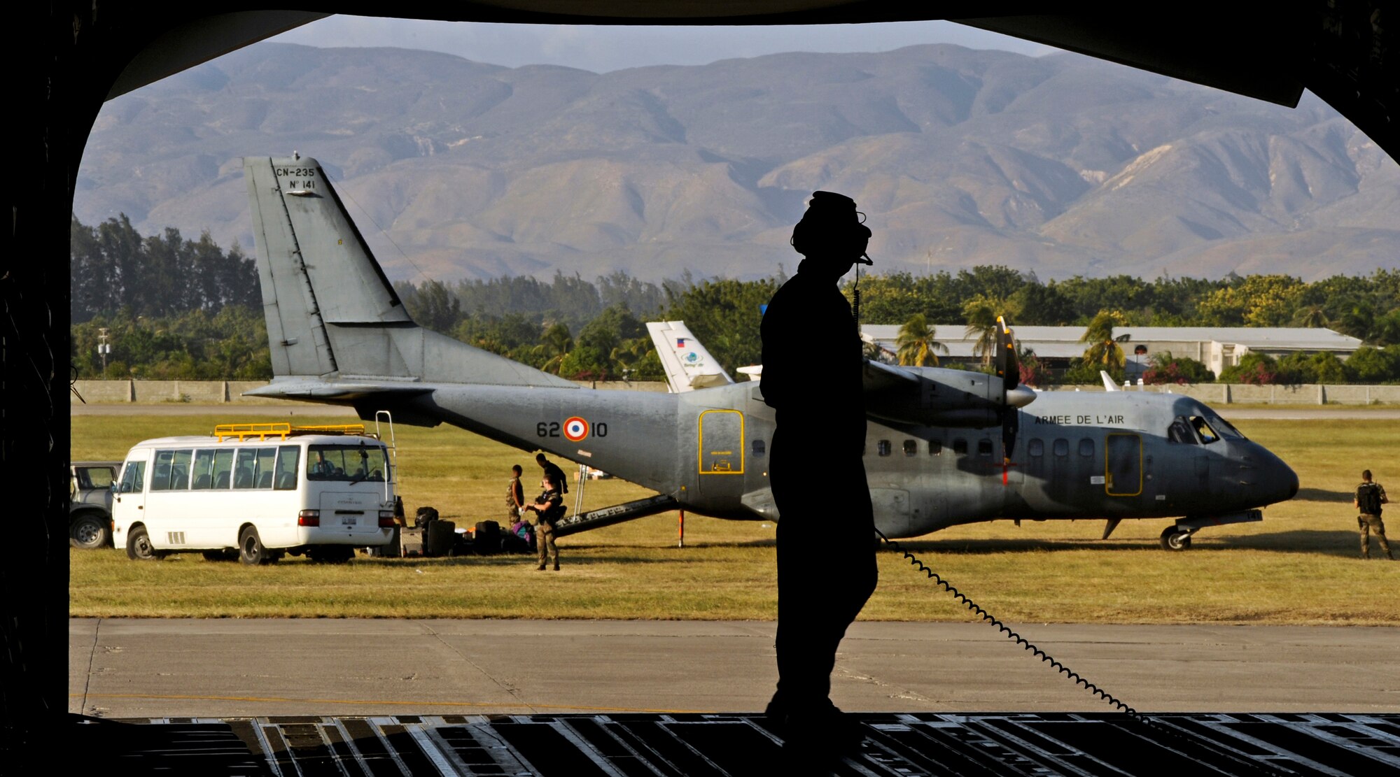 PORT-AU-PRINCE, Haiti -- Tech. Sgt. John Stone, 249th Airlift Squadron, leads communications while crews remove cargo from a C-17 Globemaster III of the 517th Airlift Squadron, from Elmendorf Air Force Base, Jan. 21. Two Humvees and a water tank were delivered to help the Haiti relief effort. (U.S. Air Force photo/Senior Airman Laura Turner)