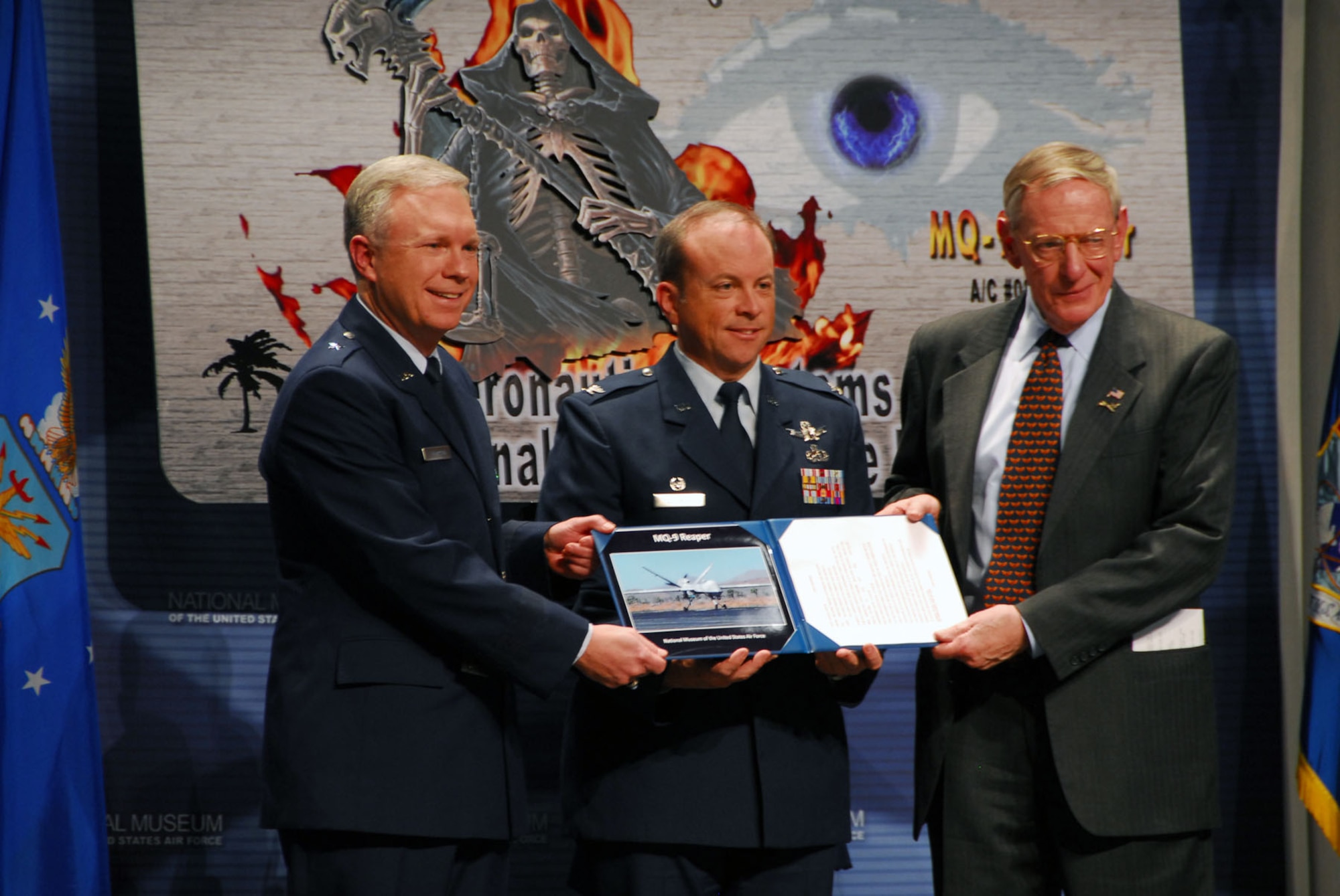 DAYTON, Ohio -- (left to right) Brig. Gen. John F. Thompson, the Air Force’s Program Executive Officer for Intelligence, Surveillance and Reconnaissance and Commander of the 303rd Aeronautical Systems Wing; Col. Christopher Coombs, Commander of the 703rd Aeronautical Systems Group; and Museum Director Maj. Gen. (Ret.) Charles D. Metcalf participate in the MQ-9 Reaper exhibit opening at the National Museum of the U.S. Air Force on Jan. 25, 2010. (U.S. Air Force photo)