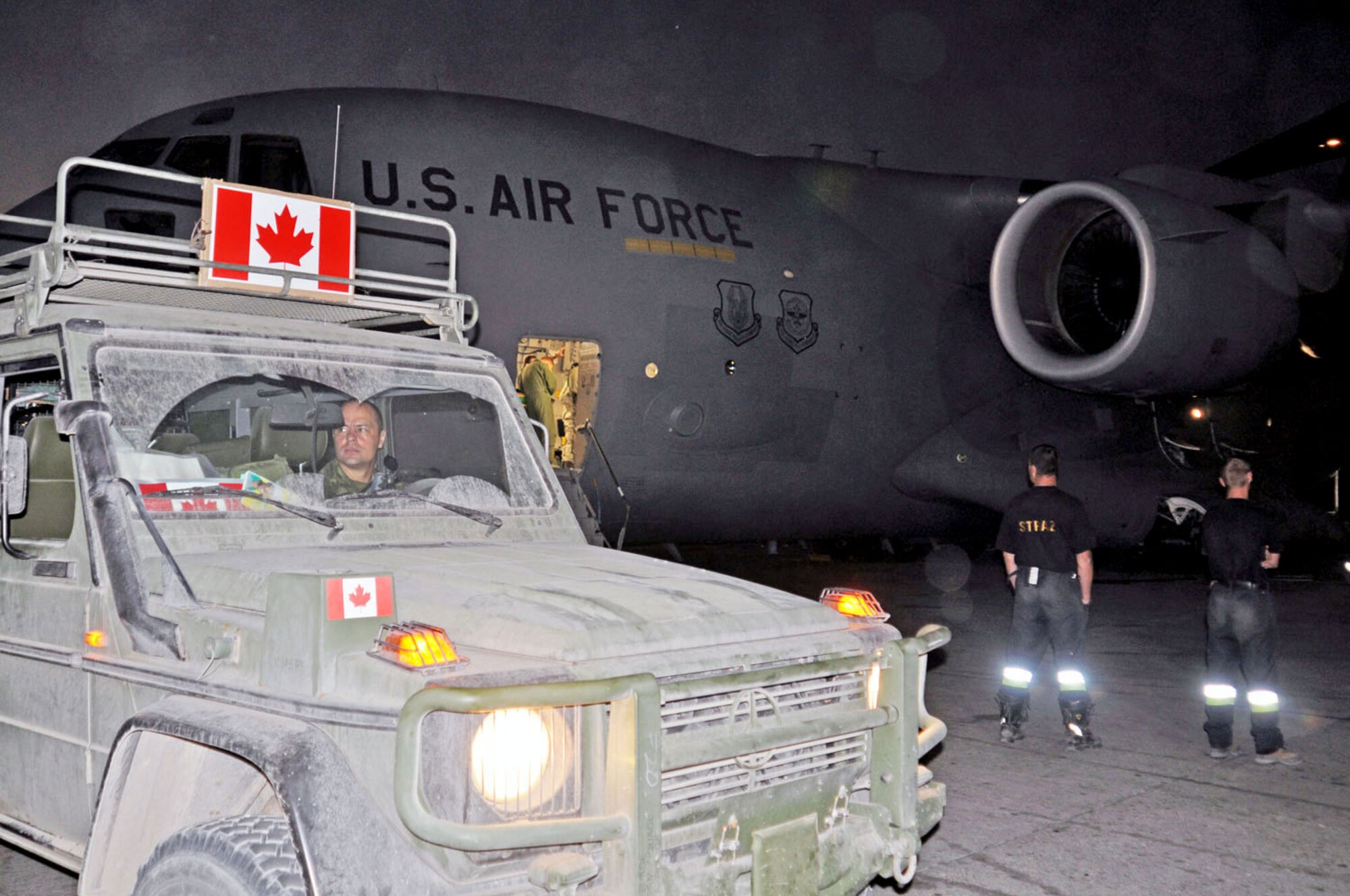 A military vehicle from Canada passes by a C-17 aircraft from March Air Reserve Base, Calif., on the ramp at Haiti’s Port-au-Prince airport Jan. 22. (U.S. Air Force photo/Kari Tilton)