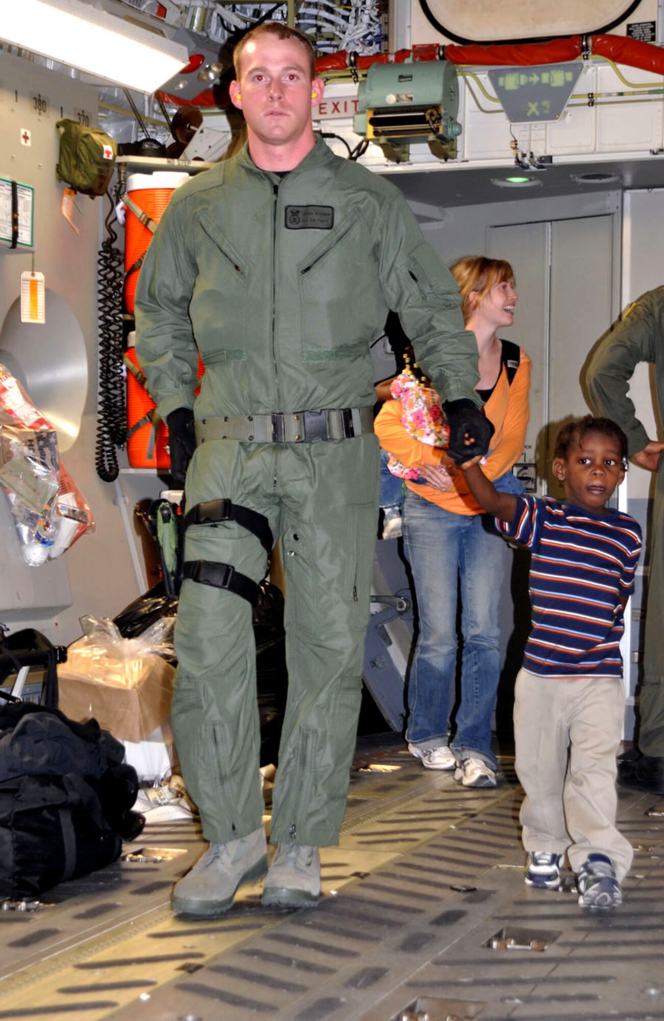 Senior Airman Joshua Osterbur, a Raven with the 62nd Security Forces Squadron at McChord Air Force Base, Wash., escorts a Haitian boy onboard an Air Force Reserve C-17 aircraft Jan. 22. The jet arrived in Haiti that afternoon with equipment and personnel from the 419th Fighter Wing’s 67th Aerial Port Squadron. It left that same night with 23 orphans headed to the United States to meet extended family members or new adoptive families. (U.S. Air Force photo/Bryan Magaña)