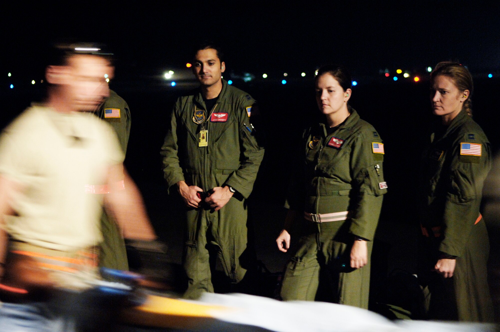 Capts. James Chongris, Angela Stephens and Kristina Lamothe (left to right), look on as patients are brought onboard a C-130 Hercules for an aeromedical evacuation mission Jan. 22, 2010 in Haiti.  Captains Chongris, Stephens and Lamothe are assigned to the 39th Airlift Squadron. (U.S. Air Force photo/2nd Lt. Nicholas Mercurio)