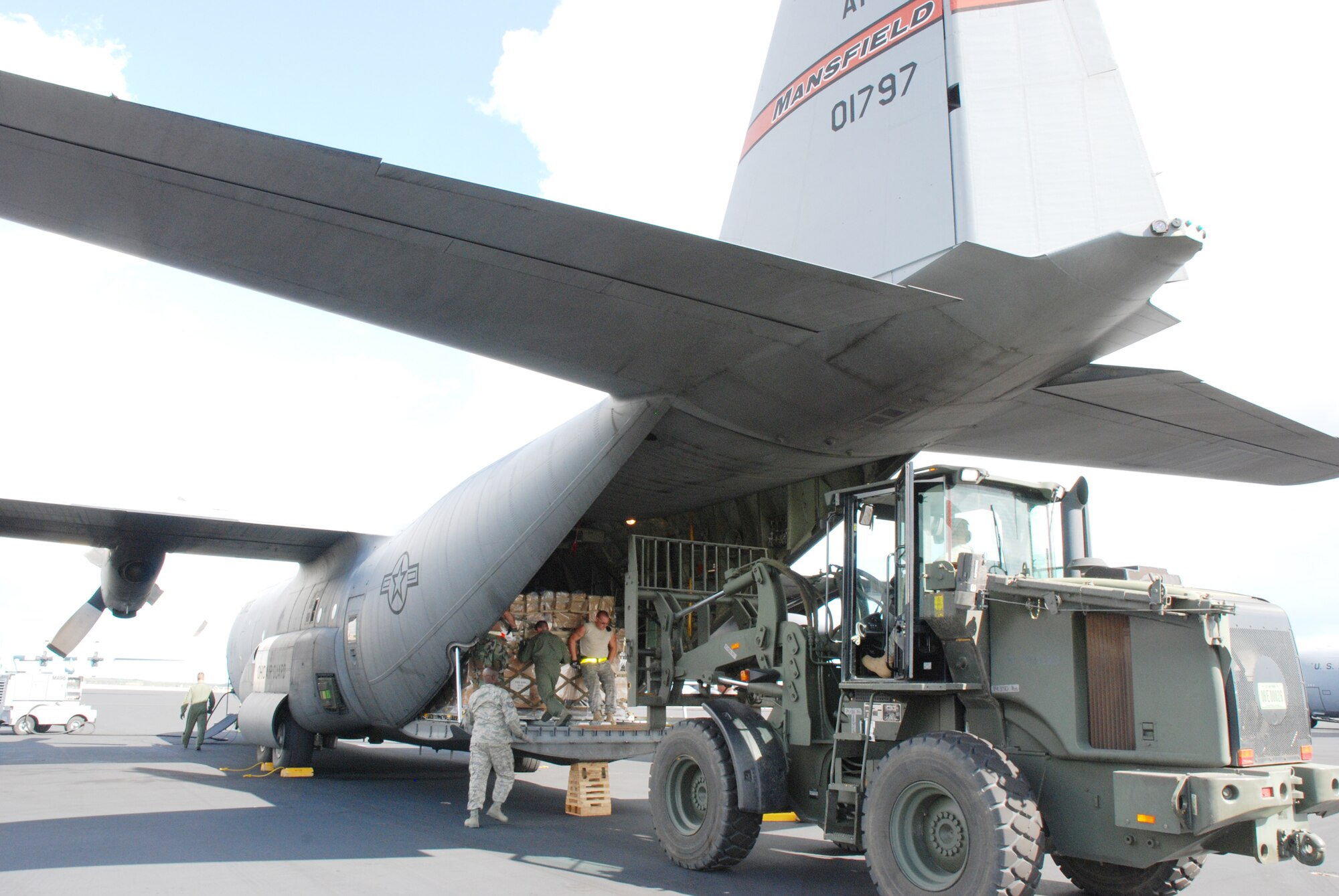 Guardsmen, reservists and active-duty Airmen load cargo on a C-130 Hercules Jan. 22, 2010, at Homestead Air Reserve Base, Fla. The C-130 is assigned to the 35th Expeditionary Airlift Squadron.  The cargo, consisting of bottled water, medical supplies and other needed items, was loaded for delivery to military forces in the Dominican Republic assisting with the earthquake relief in Haiti.  (U.S. Air Force photo/Master Sgt. Stan Coleman) 