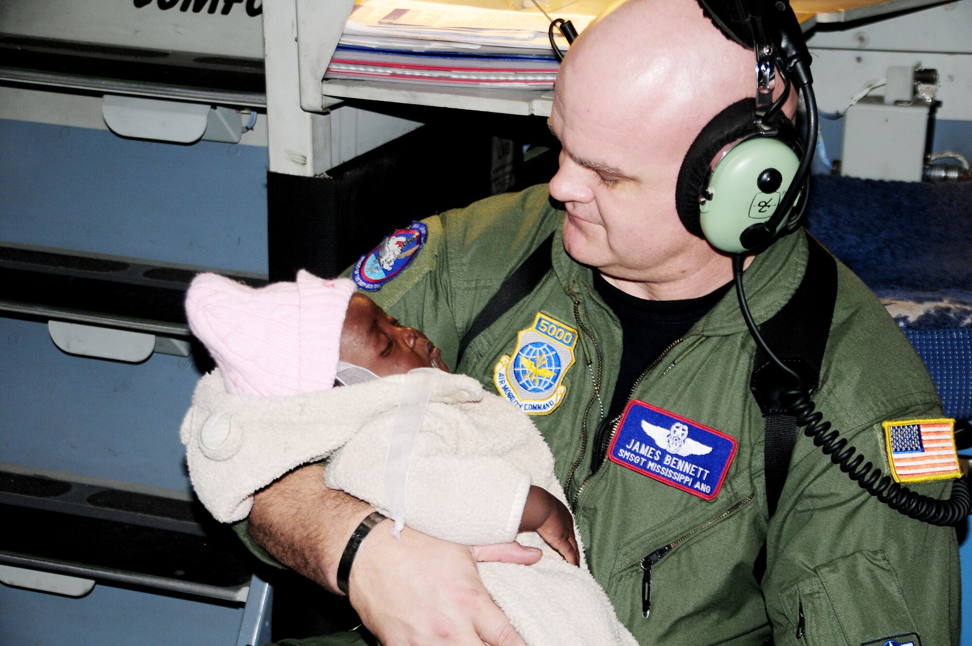 Senior Master Sgt. James Bennett takes time out from his job to hold a Haitian baby for a mother who was asleep from exhaustion Jan. 21, 2010, at the Toussaint L?Ouverture International Airport in Port-au-Prince, Haiti. Sergeant Bennett is a C-17 Globemaster III loadmaster with the Air National Guard. (U.S. Air Force photo/Master Sgt. Alvin Johnson)