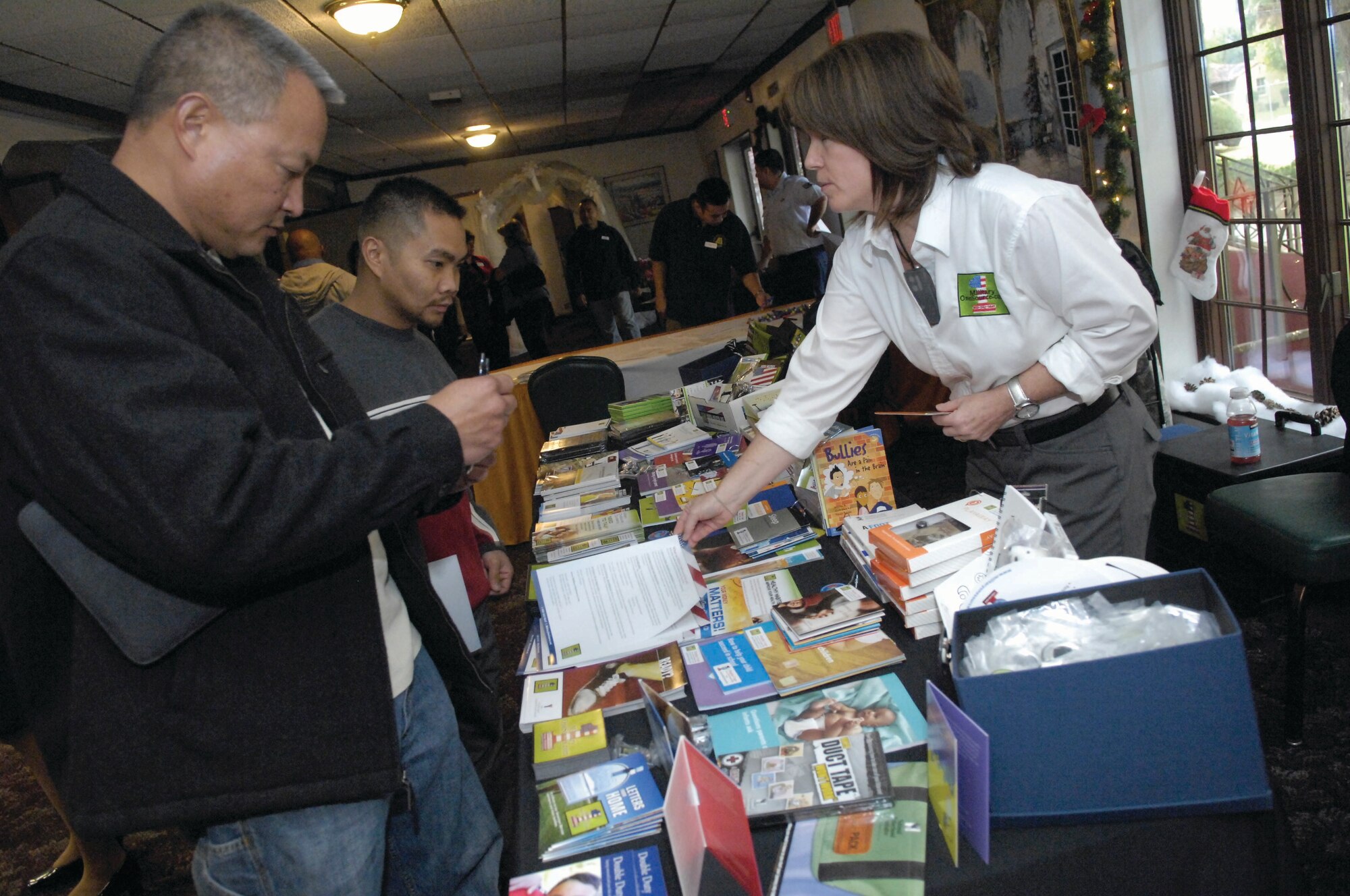A representative from Military One Source distributes information to two Yellow Ribbon Reintegration Program participants Dec. 11, 2009.  The hallway at the Hap Arnold Conference Center was filled with informational tables from organizations ranging from the Department of Veterans Affairs to the American Red Cross.