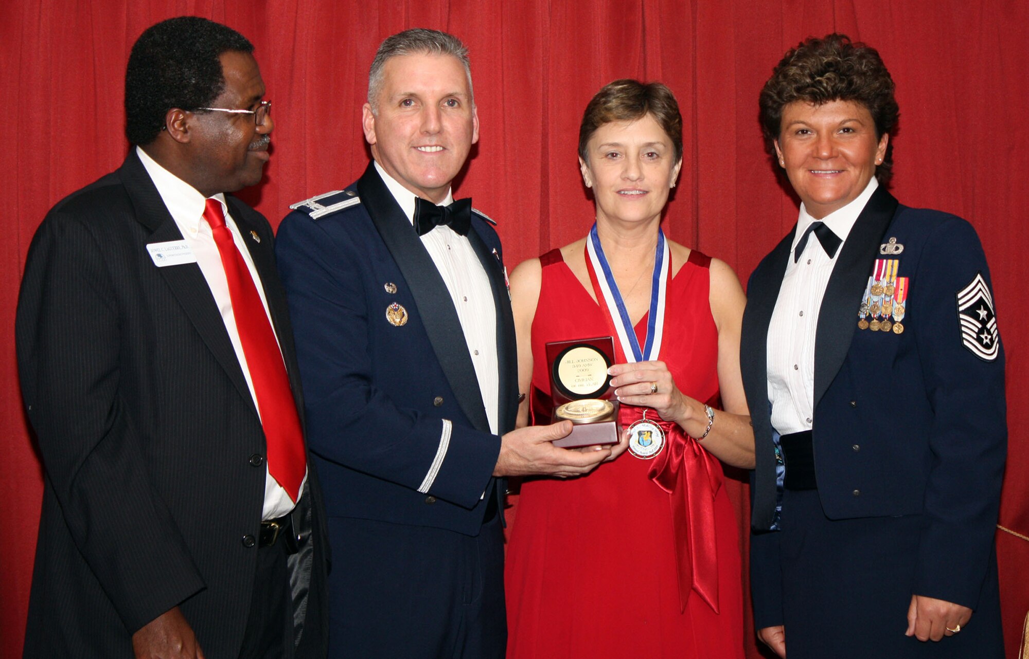 TRAVIS AIR FORCE BASE, Calif. -- It’s was the occasion of the year for the members of the 349th Air Mobility Wing; this night where the wing members are recognized for their accomplishments and contributions to the wing mission. It’s was the 349th Annual Awards Banquet, Jan 23.  More than 200 community leaders, wing members, their families and friends came together to celebrate the daily endeavors of wing members that were there to be honored.  Mrs. Jill M. Johnson, 349th Air Mobility Wing headquarters administrative assistant, won the 349th AMW Civilian of the Year award Saturday at the Delta Breeze Club here. Presenting the award (left to right) are Dr. Jowell C. Laguerre, the 349th AMW honorary commander, Col. John C. Flournoy, 349th AMW commander, and Chief Master Sgt. Kathleen R. Buckner, 349th AMW command chief. (U.S. Air Force photo/Master Sgt. Robert Wade)