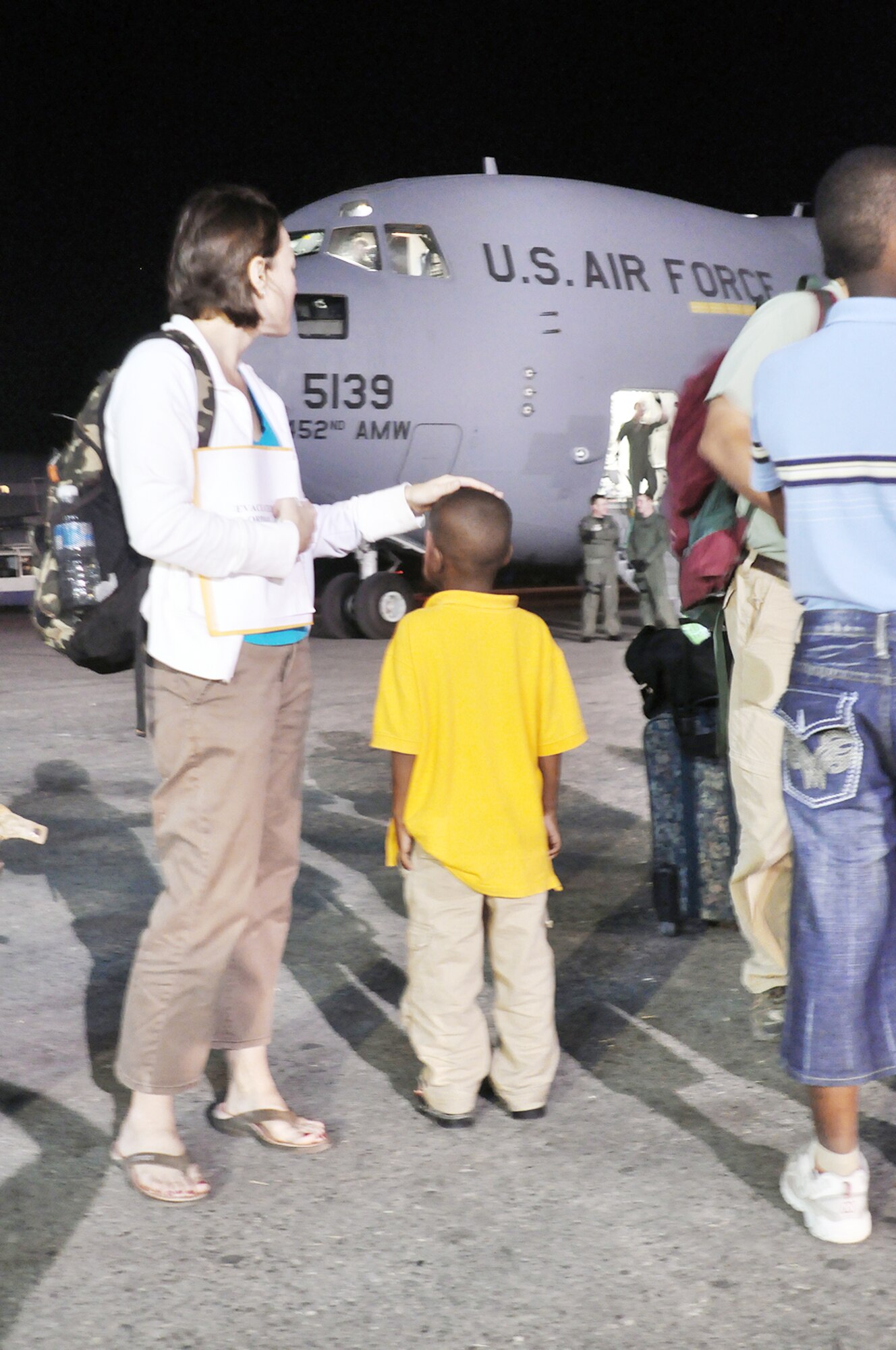 Erin Pemungia and her newly adopted 7-year-old son, Noah, wait to board a C-17 Globemaster III Jan. 22, 2010, at Port-au-Prince, Haiti. The aircraft traveled to Haiti to deliver 15 people and equipment from the 67th Aerial Port Squadron, from Hill Air Force Base, Utah. The C-17 is from the 452nd Air Mobility Wing, March Air Force Base, Calif. (U.S. Air Force photo/Kari Tilton)