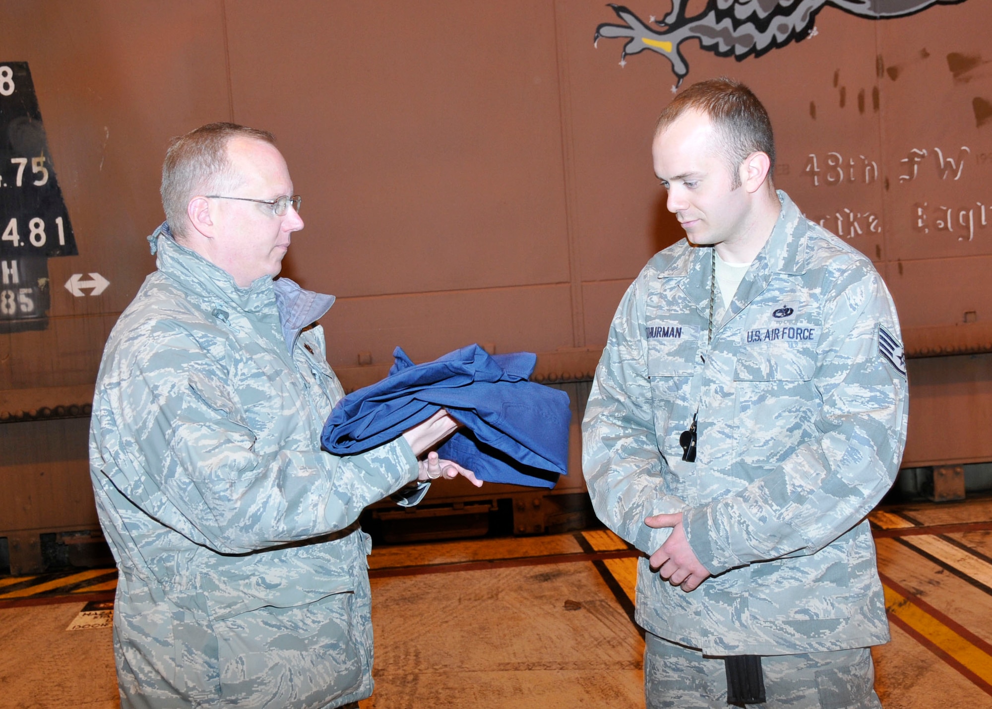 Maj. Darrin Dronoff, 748th Aircraft Maintenance Squadron commander presents Staff Sgt. Christopher Thurman 748th AMXS crew chief, with embroidered cover-alls after being named a dedicated crew chief at RAF Lakenheath, England Jan 4. More than 20 crew chiefs were given the elevated title of dedicated crew chief for superior performance and knowledge of their job. (U.S. Air Force photo/ Airman 1st Class Eboni Knox)