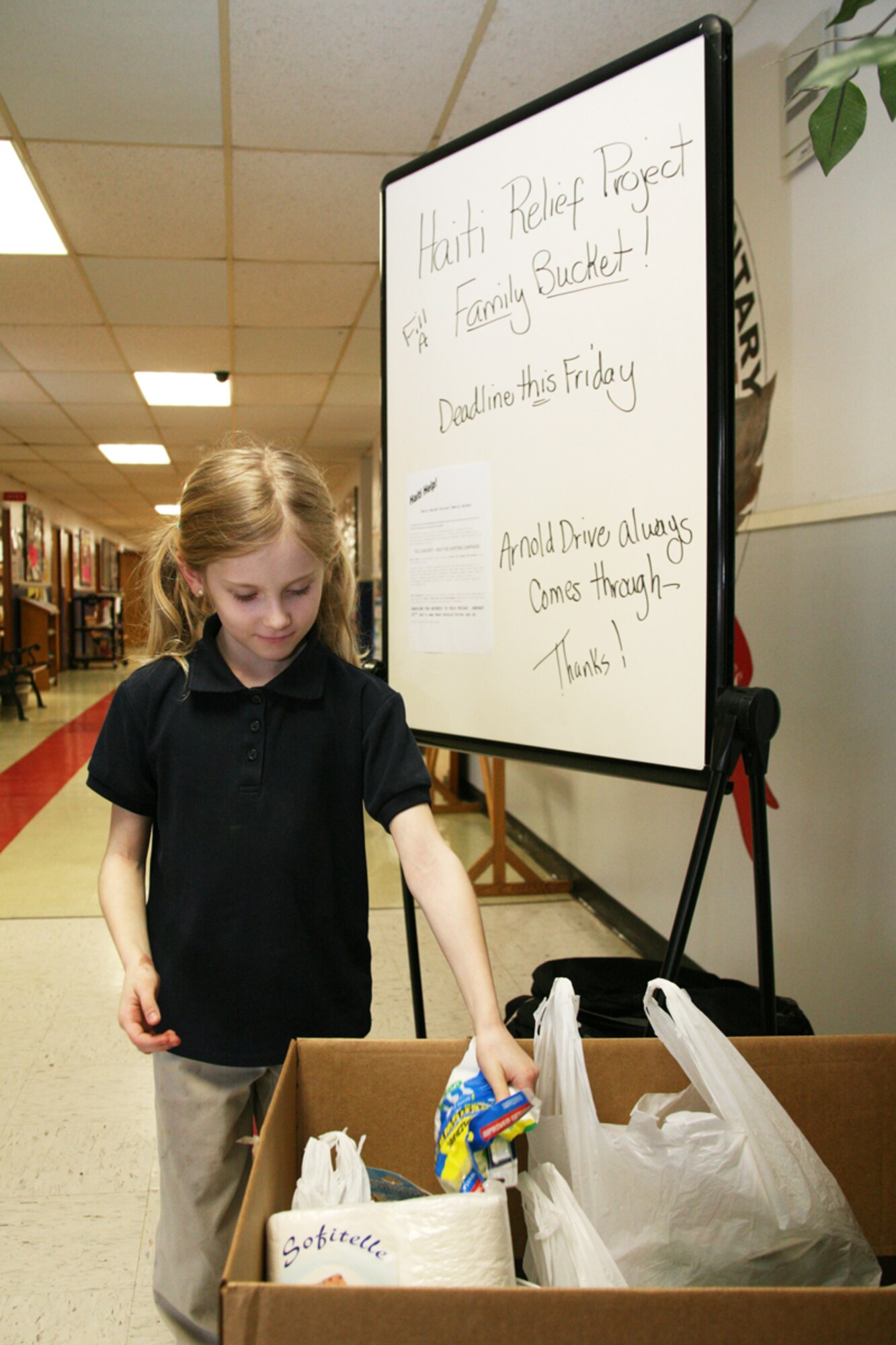 Scarlett Gillan, 8, daughter of Aubrey and Tech. Sgt. Michael Gillan, 41st Airlift Squadron, donates items Jan. 21 for the Arnold Drive Elementary School's 'Help The Hurting Campaign,' a Haiti relief project. The campaign, organized by the Sherwood Church of Christ, will deliver donated items to the church's missionaries in Haiti for distribution. Each class was asked to fill a bucket. Each bucket's contents, valued at $35 each, included bowls, spoons, cups and personal hygiene items, such as toothpaste and razors. The school's project wrapped up Jan. 22 with 23 buckets of items collected. (U.S. Air Force photo by Bob Oldham)