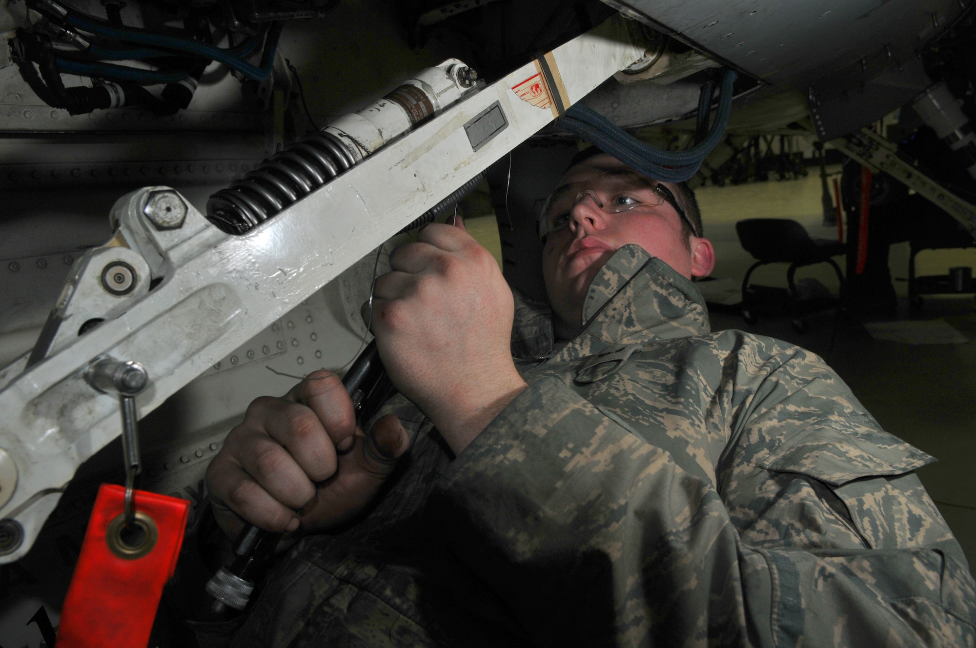 SPANGDAHLEM AIR BASE, Germany -- Airman 1st Class Kyle Chipman, 52nd Equipment Maintenance Squadron F-16 Fighting Falcon crew chief, safety wires a hydraulic line on an F-16's nose landing gear in Hangar 2 Jan. 21. Every six years the F-16's landing gear is refurbished. (U.S. Air Force photo/Airman 1st Class Nick Wilson)