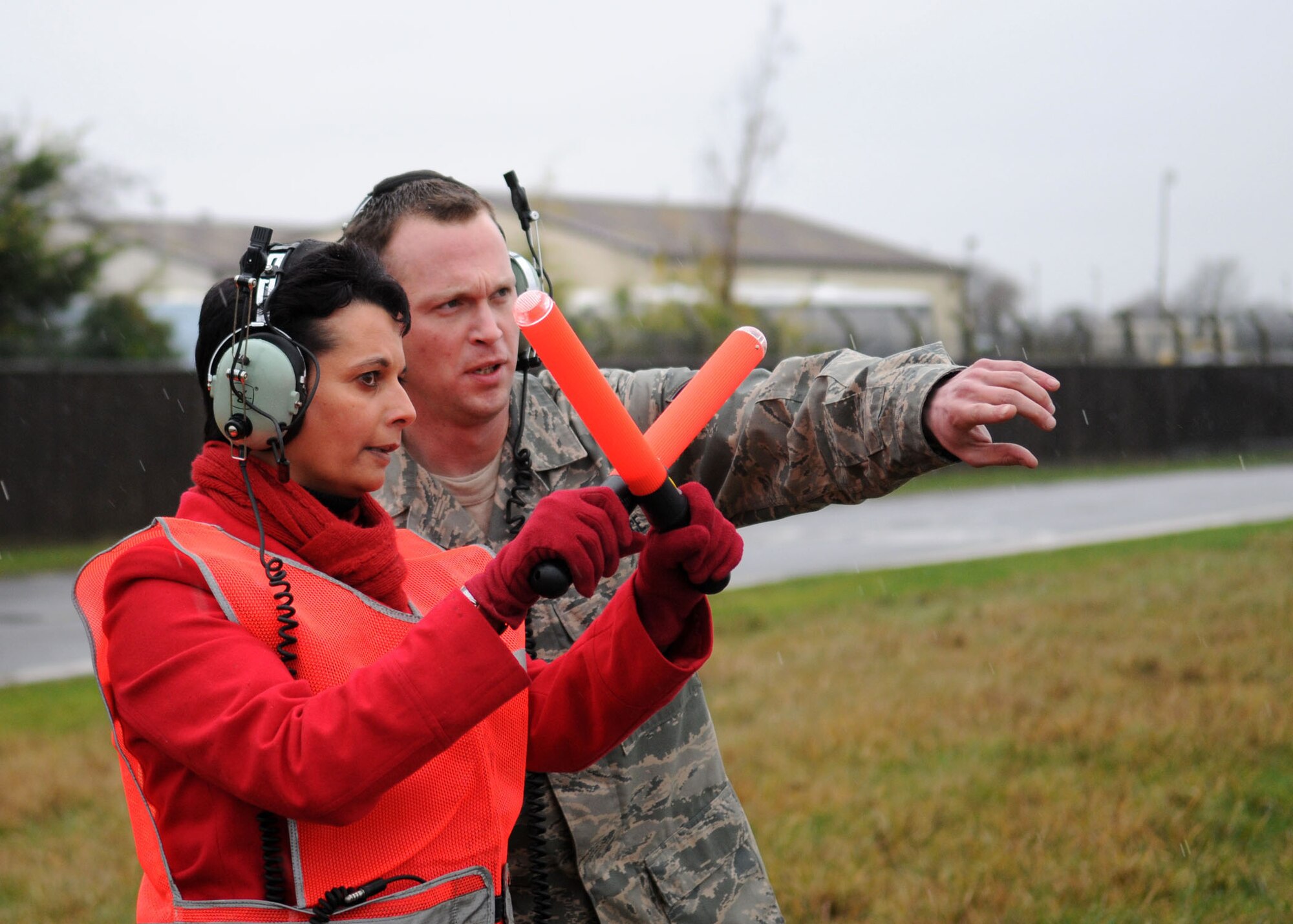 Staff Sgt. Glenn Hendrix, right, 100th Aircraft Maintenance Squadron, stands in the rain and shouts directions to Karen Abeyasekere, 100th Air Refueling Wing Public Affairs, as she assists in marshaling a KC-135 Stratotanker prior to takeoff Jan. 22, 2010. Sergeant Hendrix, from Williamsburg, Ind., is a crew chief and regularly marshals RAF Mildenhals fleet of aircraft. (U.S. Air Force photo by Staff Sgt. Jerry Fleshman)