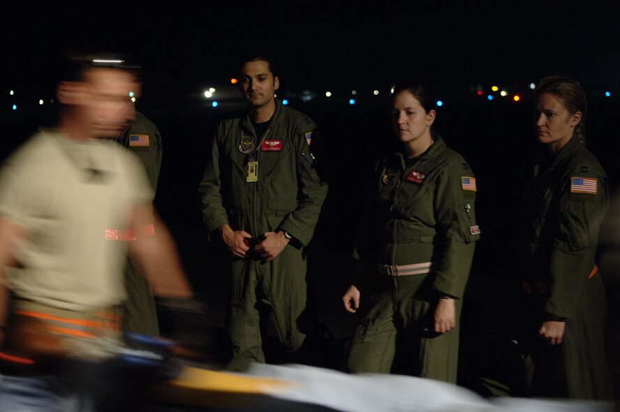 Capts. James A. Chongris, Angela L. Stephens and Kristina L. Lamothe (left to right), 39th Airlift Squadron, Dyess Air Force Base, Texas, look on as patients are brought onboard a C-130H for an aeromedical evacuation mission Jan. 22, 2010. In less than six hours from the time the first patient was loaded, all four critical-care patients on the aircraft were offloaded at Miami International Airport and transported to area hospitals. (U.S. Air Force Photo/2nd Lt. Nicholas Mercurio) 