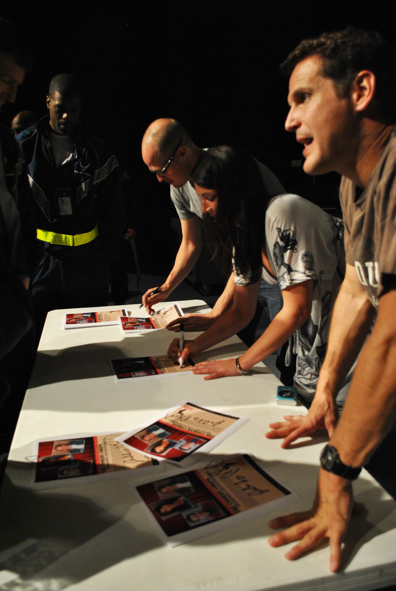 Matt Baetz, Lauren Ashley Bishop and Johnny Cardinale, Comedy Corps performers, autograph show flyers for servicemembers following a performance of the "Disarmed and Dangerous" comedy show at the Coalition Compound Theatre at a non-disclosed Southwest Asia location, Jan. 23, 2010. The comedy troupe is scheduled to appear at various locations throughout the AOR. (U.S. Air Force photo by Senior Master Sgt. David Byron) [RELEASED]