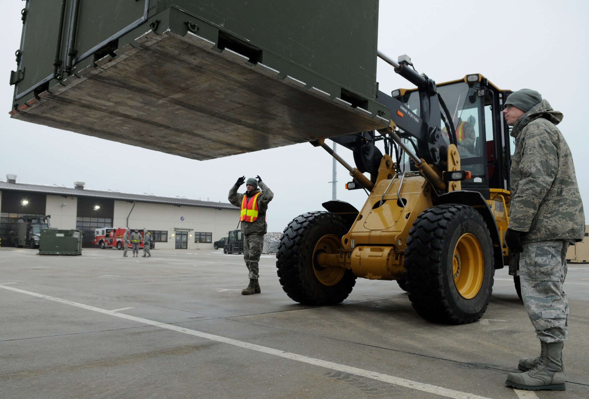 SPANGDAHELM AIR BASE, Germany – Airman Johnny Sanes, 52nd Logistics Readiness Squadron, and Senior Airman Aaron Krippner, 52nd Communications Squadron, direct Airman 1st Class Justin Shepherd, 52nd LRS, as he drives a 10,000-pound, all-terrain forklift to load equipment onto a truck during Operation Saber Crown 10-3 here Jan. 21. This exercise was the first at Spangdahlem to have a cargo deployment function consisting of Airmen augmented from across the wing. (U.S. Air Force photo/Senior Airman Benjamin Wilson)