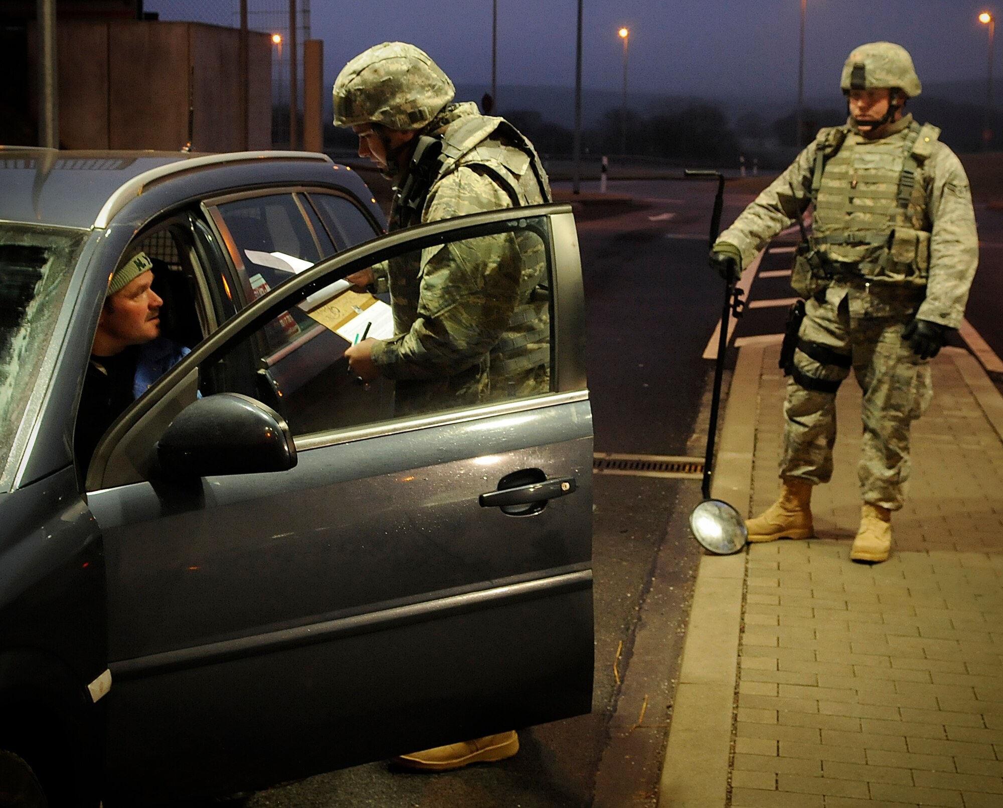SPANGDAHLEM AIR BASE, Germany – Airman Thomas Sisler, 52nd Security Forces Squadron, checks the credentials of a person entering Spangdahlem Air Base while Airman 1st Class Devin Cross, 52nd SFS, prepares to conduct a vehicle search during Operation Saber Crown 10-03 Jan. 20. Members of the 52nd SFS were required to randomly search vehicles entering the base as part of increased security measures for the exercise. (U.S. Air Force photo/Senior Airman Benjamin Wilson)