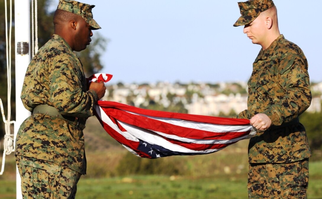 Sgt. Marchello M. McCullough (left), administrative clerk, Deployment Processing Command West, Camp Talega, folds a flag with Sgt. Harry J. Lang, administrative clerk, DPCW, that will be given to Air Force Lt. Col. Hai N. Tran. Tran is retiring after nearly 20 years of service and coming to America as a Vietnam refugee. Camp Talega is where he and thousands of refugees lived in tent cities before being granted citizenship.::r::::n::
