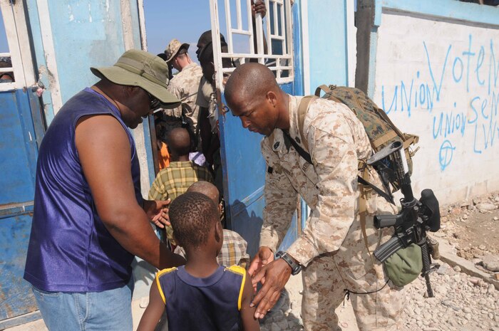 Marine Staff Sgt. Christopher D. Thomas, from Franklin, La., guides children to a humanitarian aid distribution point in Saint Marc, Haiti. Nassau is supporting Operation Unified Response following a 7.0 magnitude earthquake that caused severe damage in Haiti, Jan. 12.