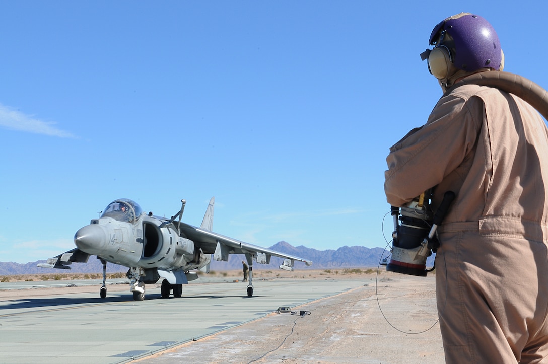 Lance Cpl. Michael Connor, Marine Wing Support Squadron 371 bulk fuel specialist, waits to refuel a Marine Attack Squadron 311 AV-8B Harrier as it taxis to the refueling point at the Auxiliary Airfield 2 in Yuma, Ariz., Jan. 25, 2010. AUX-2 is a replica of the deck of an amphibious assault ship, on which squadrons practice before working off of an actual ship at sea. The squadron started training at AUX-2 Jan. 26-28, 2010, in preparation for their carrier qualification aboard the USS Peleliu in February 2010. The squadron is scheduled to deploy to the Peleliu with the 15th Marine Expeditionary Unit in May 2010. Part of the squadron deployed to Japan with the 31st MEU in early January 2010.