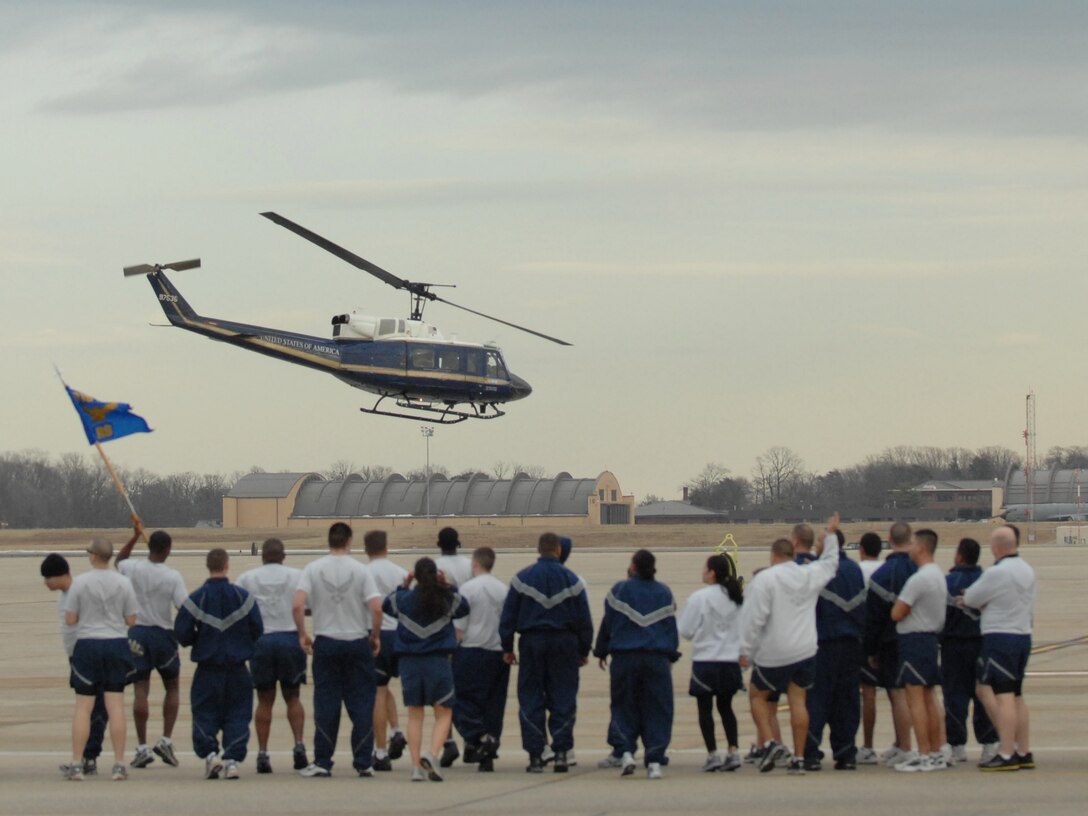 Members of the 316th Wing mark time during a wing run on the flightline while watching a 1st Helicopter Squadron UH-1 Huey helicopter take off Jan. 15, 2010. The 1 HS conducted a scramble during the run in which an alarm sounds and the pilots and flight engineers run to their helicopter and take off as quickly as possible. (U.S. Air Force by Tech. Sgt. Maritza Freeland)