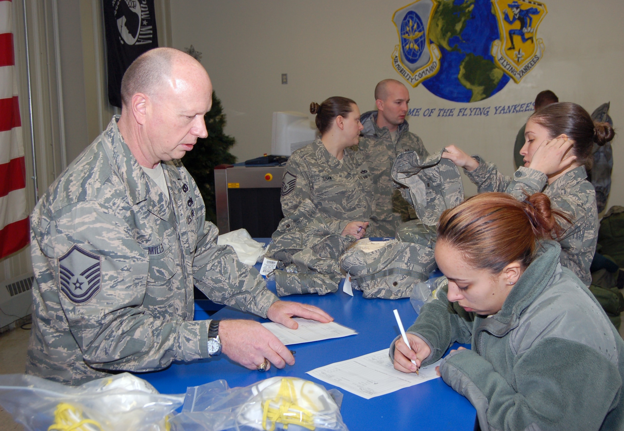 Master Sgt. David D. Miller, a logistics management specialist with the 103rd Logistics Readiness Squadron, issues dust masks to Senior Airman Danielle Cummings, a services apprentice from the 103rd Force Support Squadron, during the deployment process in the small air terminal at Bradley Air National Guard Base Jan. 25, 2009. The masks, along with utility tools and personal tents, were issued to deployers as essential equipment in order for them to complete their mission in Haiti. (U.S. Air Force photo by Tech. Sgt. Joshua Mead)