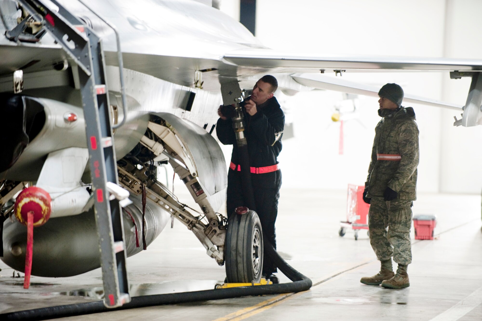 Airman 1st Class Dustin Smith (left), 13th Aircraft Maintenance Unit crew chief, attaches a fuel hose to an F-16 Fighting Falcon with Airman 1st Class Anthony Davis, 35th Logistics Readiness Squadron refueling unit operator, inside a hardened aircraft shelter Jan. 19, 2010, at Misawa Air Base, Japan. The 35th LRS fuels management flight distributes an average of 43,000 gallons of JP-8 jet fuel every 24 hours. (U.S. Air Force photo/Staff Sgt. Samuel Morse)