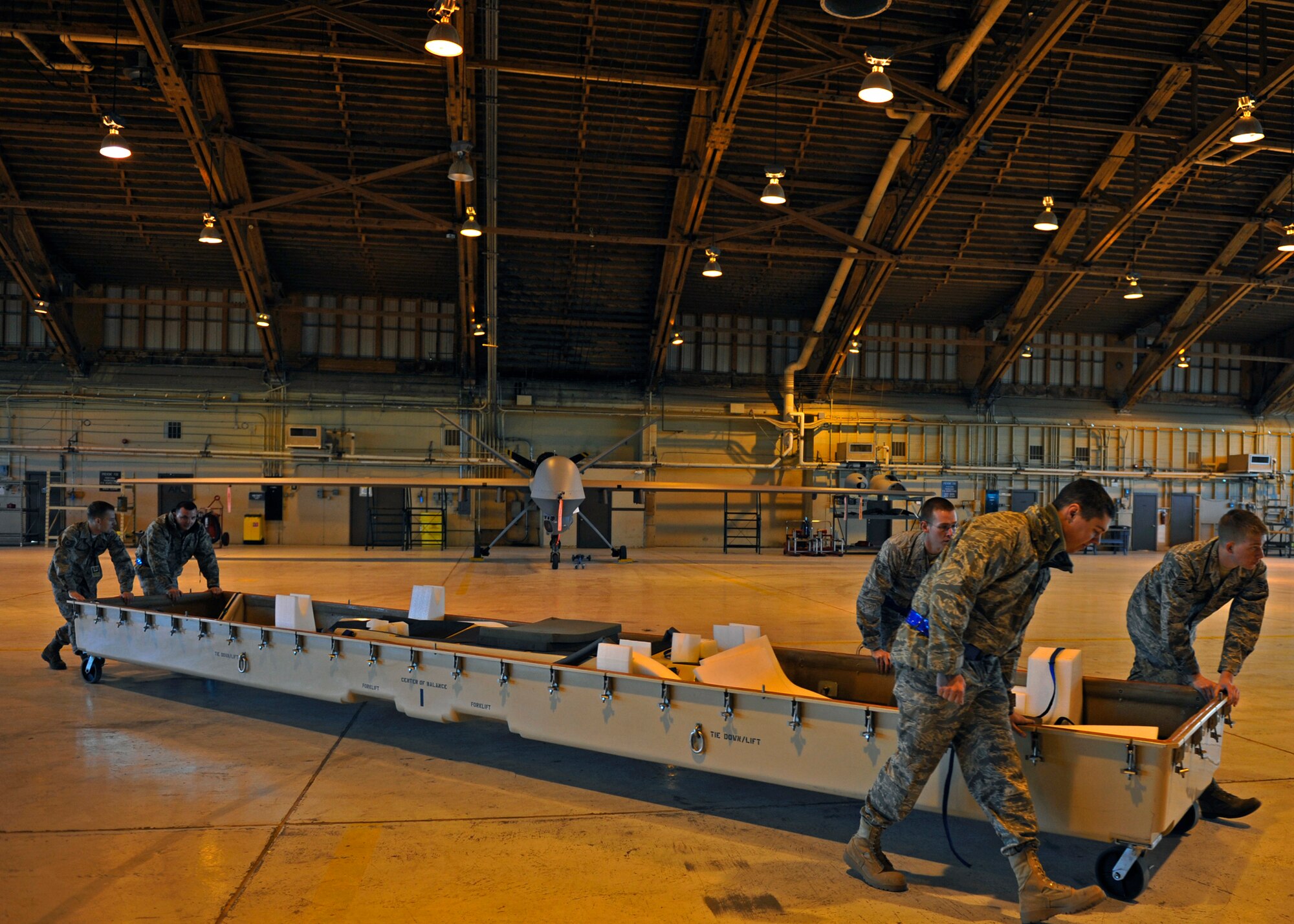 HOLLOMAN AIR FORCE BASE, N.M. -- Airmen from the 849th Aircraft Maintenance Squadron push a casket across the hangar, Jan 17. The Airmen were disassembling and packaging an RQ-1 Predator for departure in support of Operation Unified Response. (U.S. Air Force photo by Staff Sgt. Anthony Nelson Jr.)