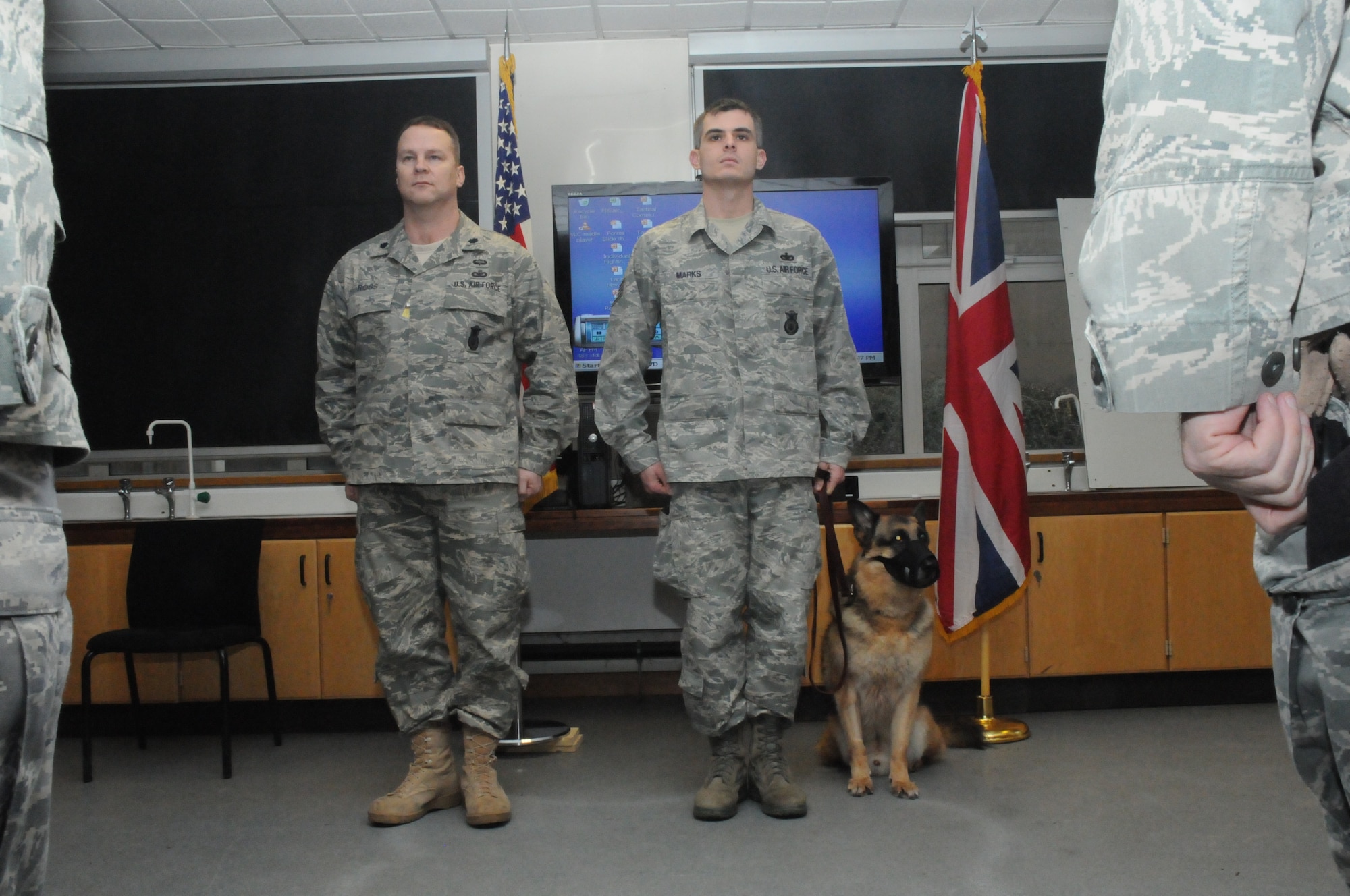 Former military working dog Dan, a German Sheppard, and handler, Staff Sgt. Michael Marks, stand at attention with Lt. Col. Michael D. Ross, 48th Security Forces Squadron commander, while being recognized for Dan’s nine years of military service during his retirement ceremony at RAF Feltwell on Jan. 13. (U.S. Air Force photo/SSgt. Megan Lyon)