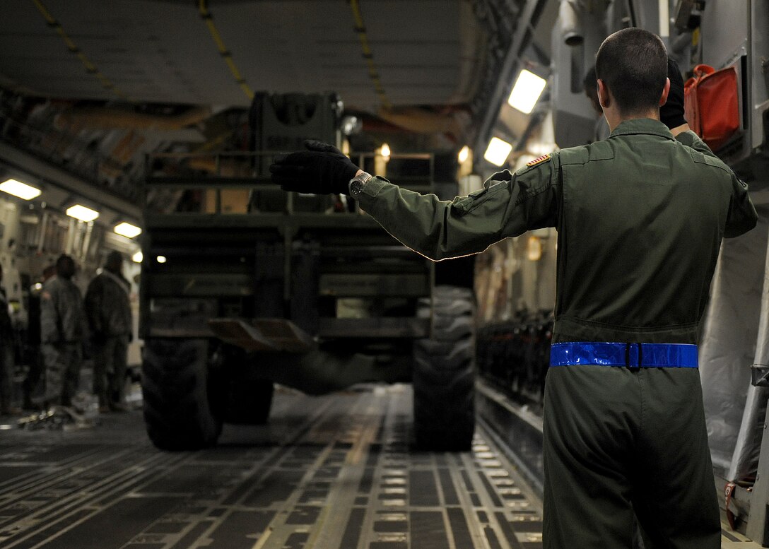 LANGLEY AIR FORCE BASE, Va. – Airman 1st Class Alec Parker, 7th Airlift Squadron loadmaster from McChord Air Force Base, Wash., directs a vehicle into the bay of a C-17 Globemaster III Jan. 22 in support Operation Unified Response, a massive movement of military personnel and supplies to aid in relief efforts following the devastating earthquake that struck Haiti on Jan. 12. Langley Airmen and U.S. Army personnel from Fort Eustis helped McChord Airmen load equipment and supplies onto the aircraft, the third of its type to transfer Peninsula efforts. (U.S. Air Force photo/ Airman Rebecca Montez)