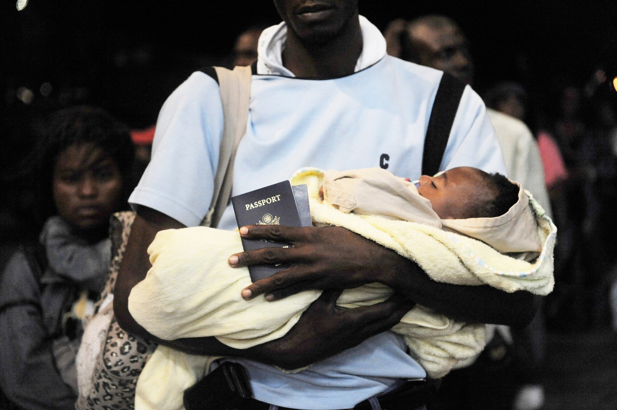 A U.S. citizen in Haiti holds his child and passport before boarding a C-17 Globemaster III for a flight back to the United States Jan. 20, 2010 at Toussaint L'Ouverture International Airport in Port-au-Prince, Haiti. The U.S. Air Force is flying U.S. citizens in Haiti back to the U.S. following an earthquake Jan. 12 that leveled much of the country's infrastructure. (U.S. Air Force photo/Staff Sgt. Jason Robertson