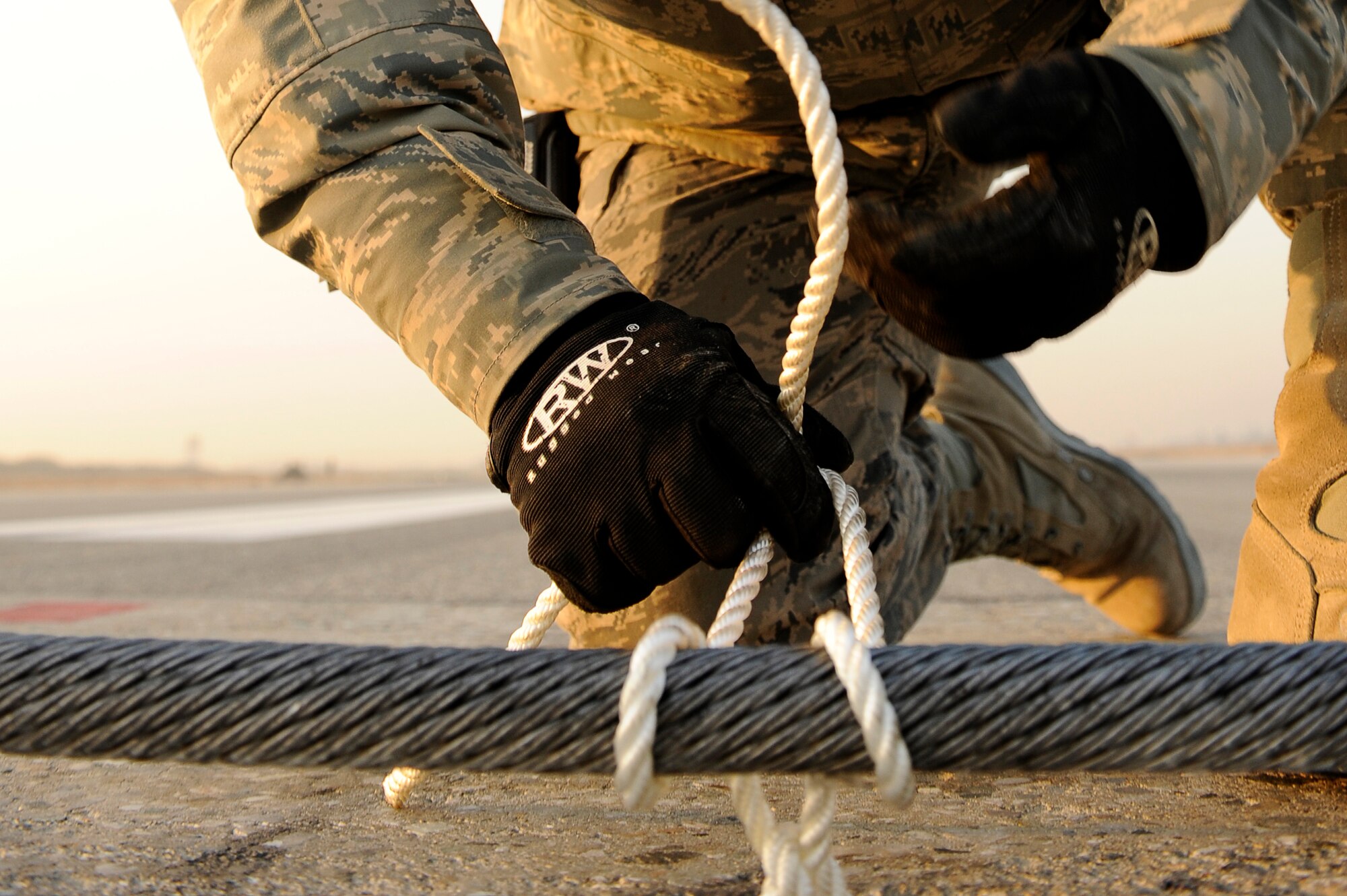 BAGRAM AIRFIELD, Afghanistan--U.S. Air Force Master Sgt. Dave Rink, 455th Expeditionary Civil Engineer Squadron, ties down an arresting cable at Bagram Airfield, Jan. 15, 2010. Rink is a member of the Minnesota National Guard from Superior, Wis. (U.S. Air Force photo by: Tech. Sgt. Jeromy K. Cross/released) 