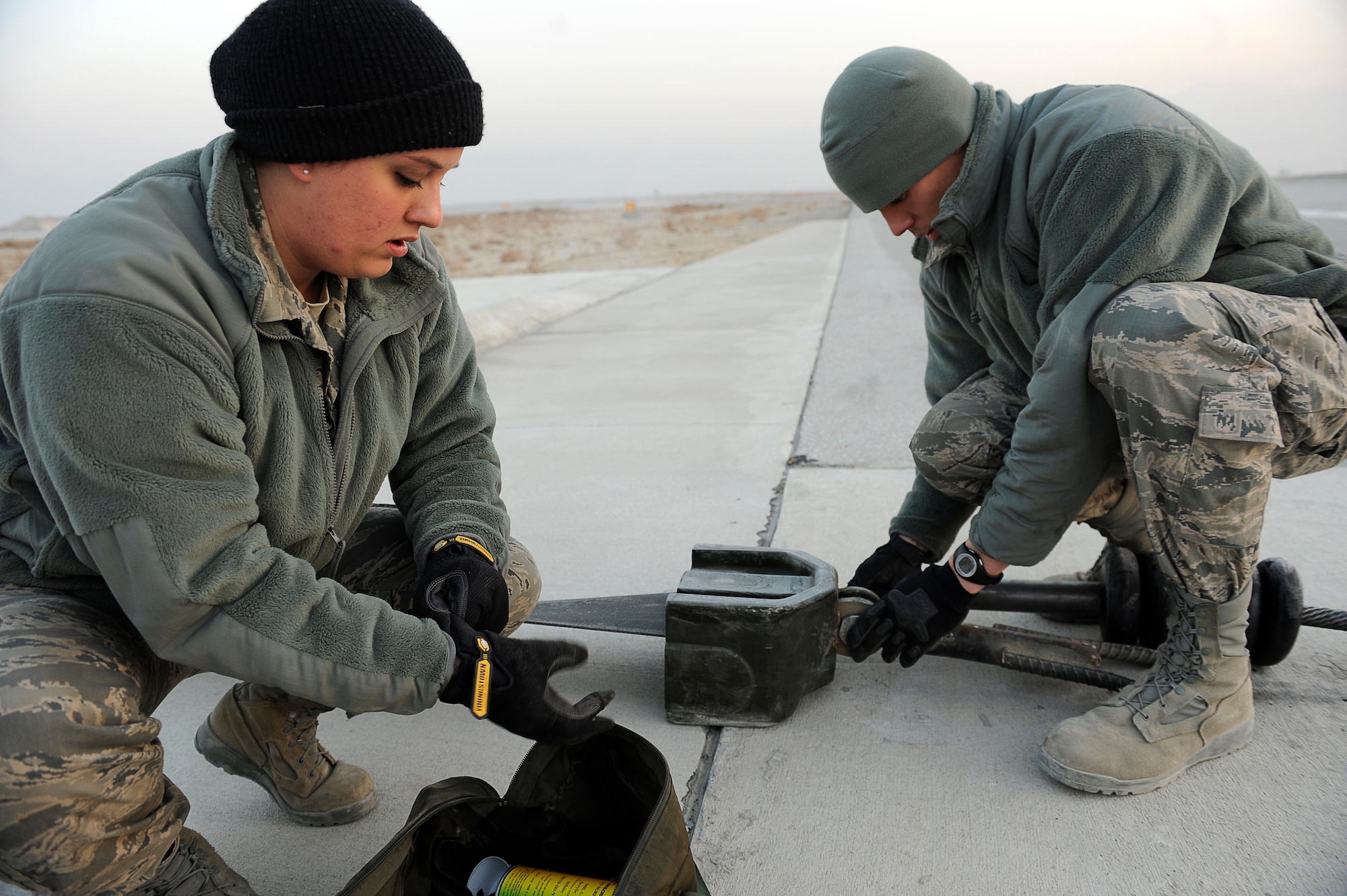 BAGRAM AIRFIELD, Afghanistan--U.S. Air Force Senior Airman Melissa Gillett (near), and Staff Sgt. Eric Austin, 455th Expeditionary Civil Engineer Squadron, maintain an arresting cable at Bagram Airfield, Jan. 15, 2010. Gillett is from Duluth, Minn., and Austin is from Superior, Wis., both are members of the Minnesota National Guard. (U.S. Air Force photo by: Tech. Sgt. Jeromy K. Cross)
