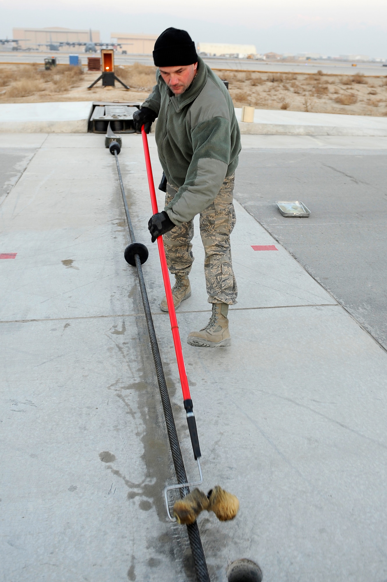 BAGRAM AIRFIELD, Afghanistan--U.S. Air Force Staff Sgt. Mike Cole, 455th Expeditionary Civil Engineer Squadron, applies lubricant to an arresting cable at Bagram Airfield, Jan. 15, 2010. Cole is a member of the Minnesota National Guard from Duluth, Minn. (U.S. Air Force photo by: Tech. Sgt. Jeromy K. Cross)