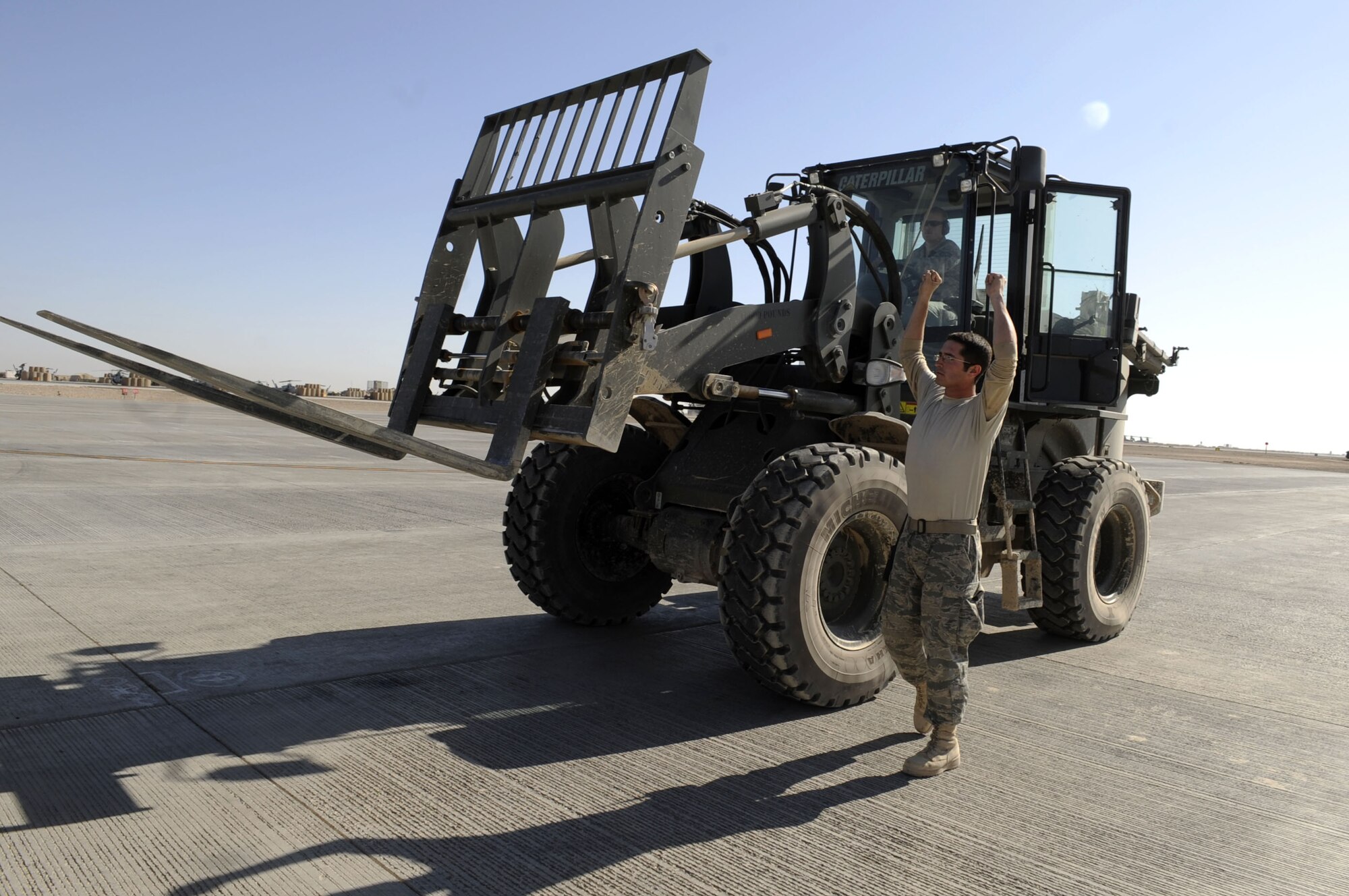 Airman 1st Class Joshua McGee, Air Terminal Operations Center ramp controller, directs Staff Sgt. Daryl Tigert, driving a 10K forklift, to receive the mail off the DC8 aircraft at Camp Bastion, Jan. 20, 2010.  Airman McGee is from the 3rd Aerial Port Squadron, Pope AFB, N.C., and Sergeant Tigert is from the 573rd Global Support Squadron.  (U.S. Air Force photo/Senior Airman Nancy Hooks/Released)